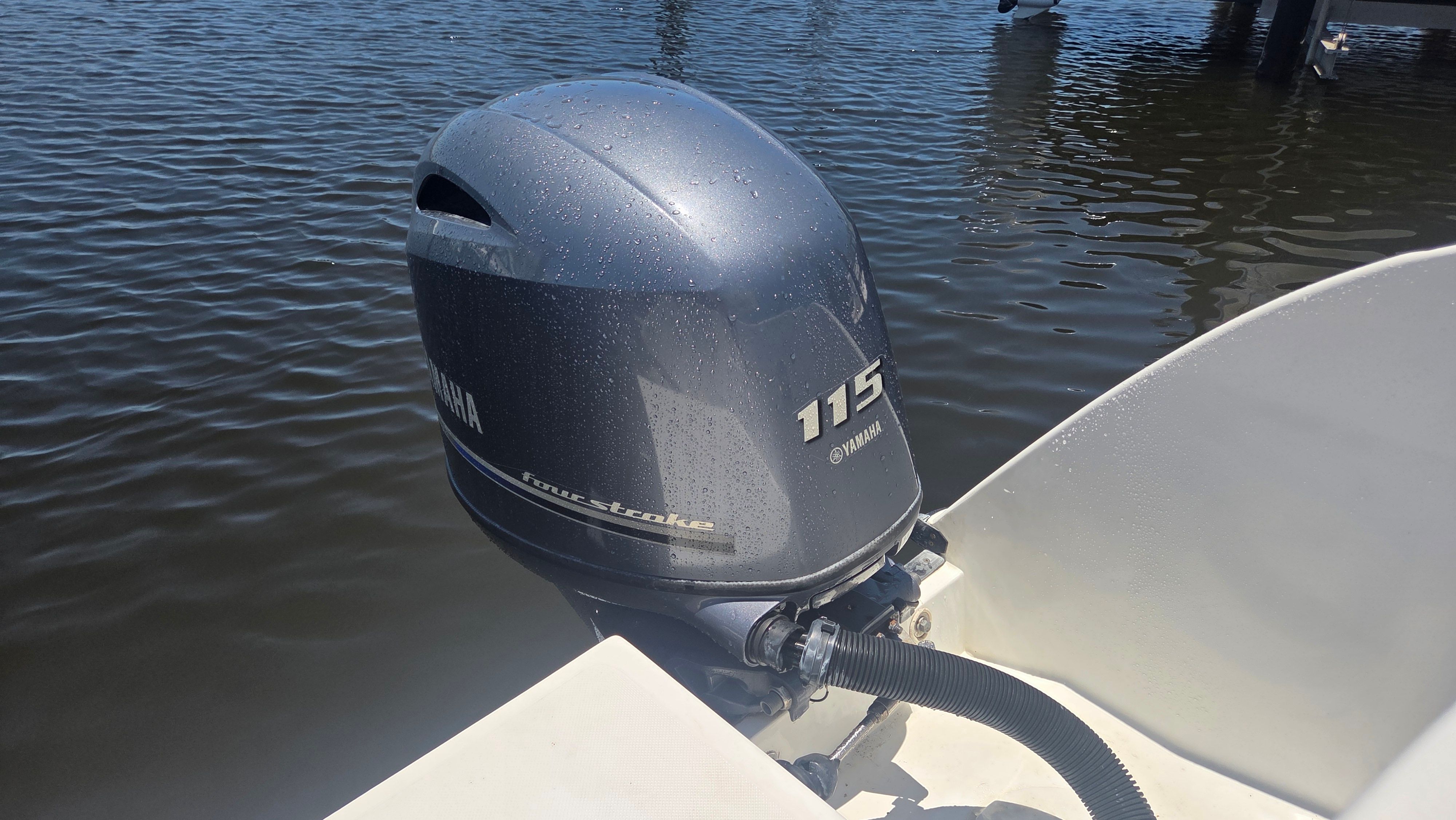 A Yamaha 115 outboard motor on a boat in calm water.