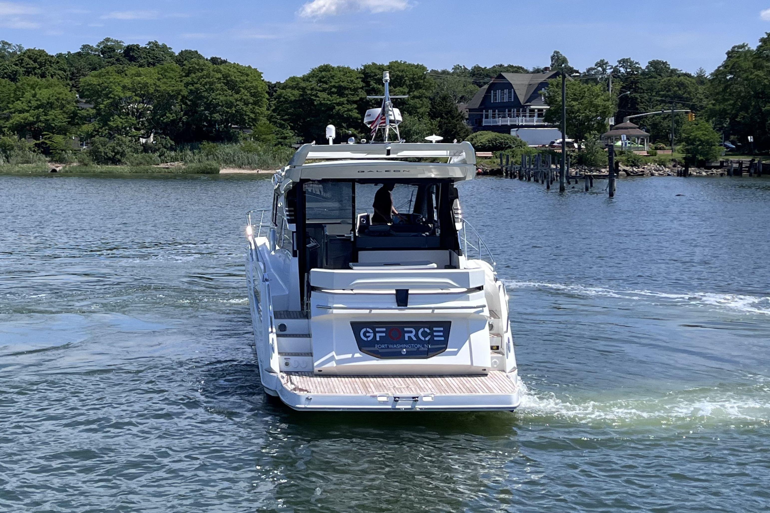 2024 Galeon 425 HTS yacht cruising on a serene lake with lush greenery.