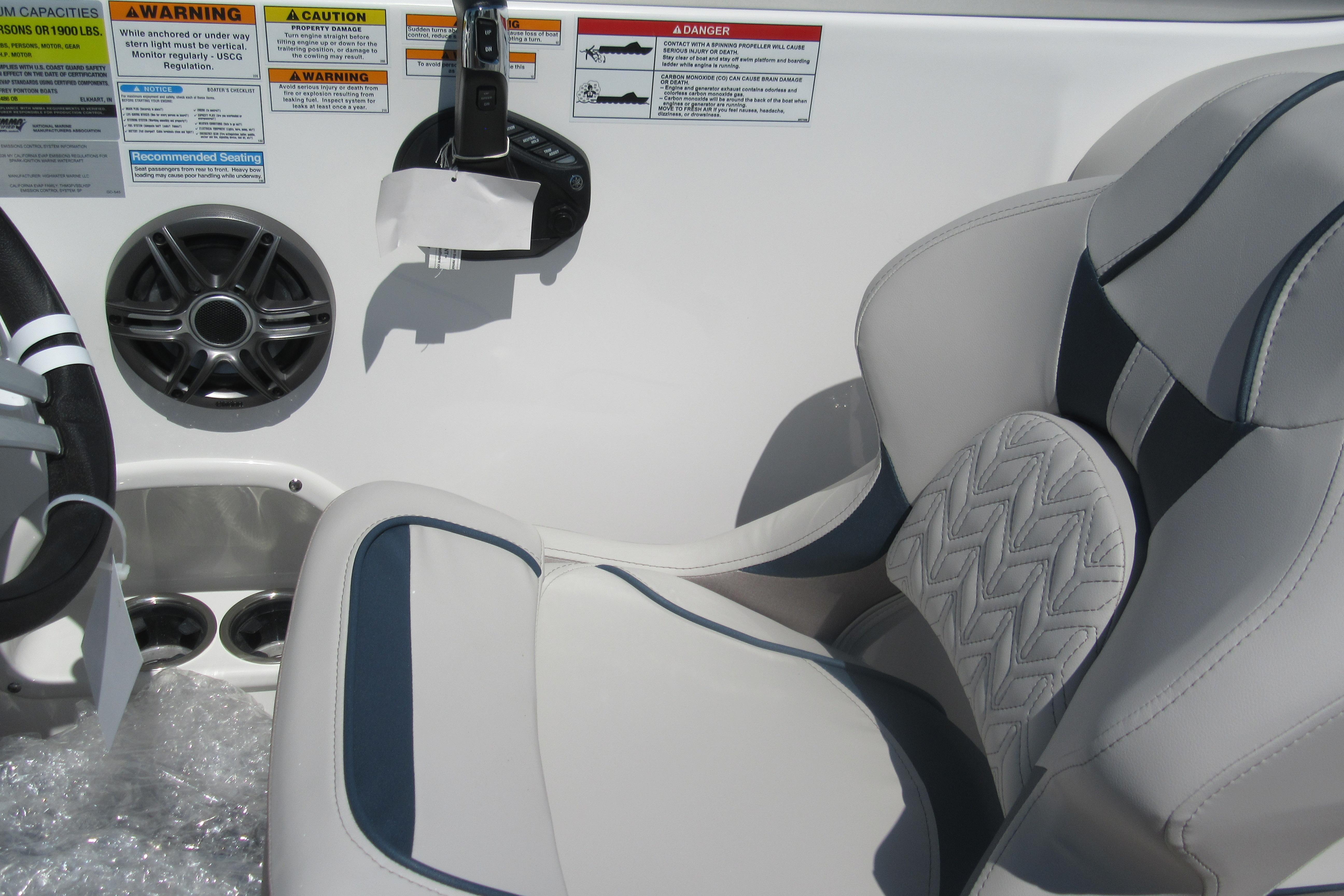 2027 Hurricane SunDeck 2486 OB boat interior with steering wheel, speaker, and cushioned seat.