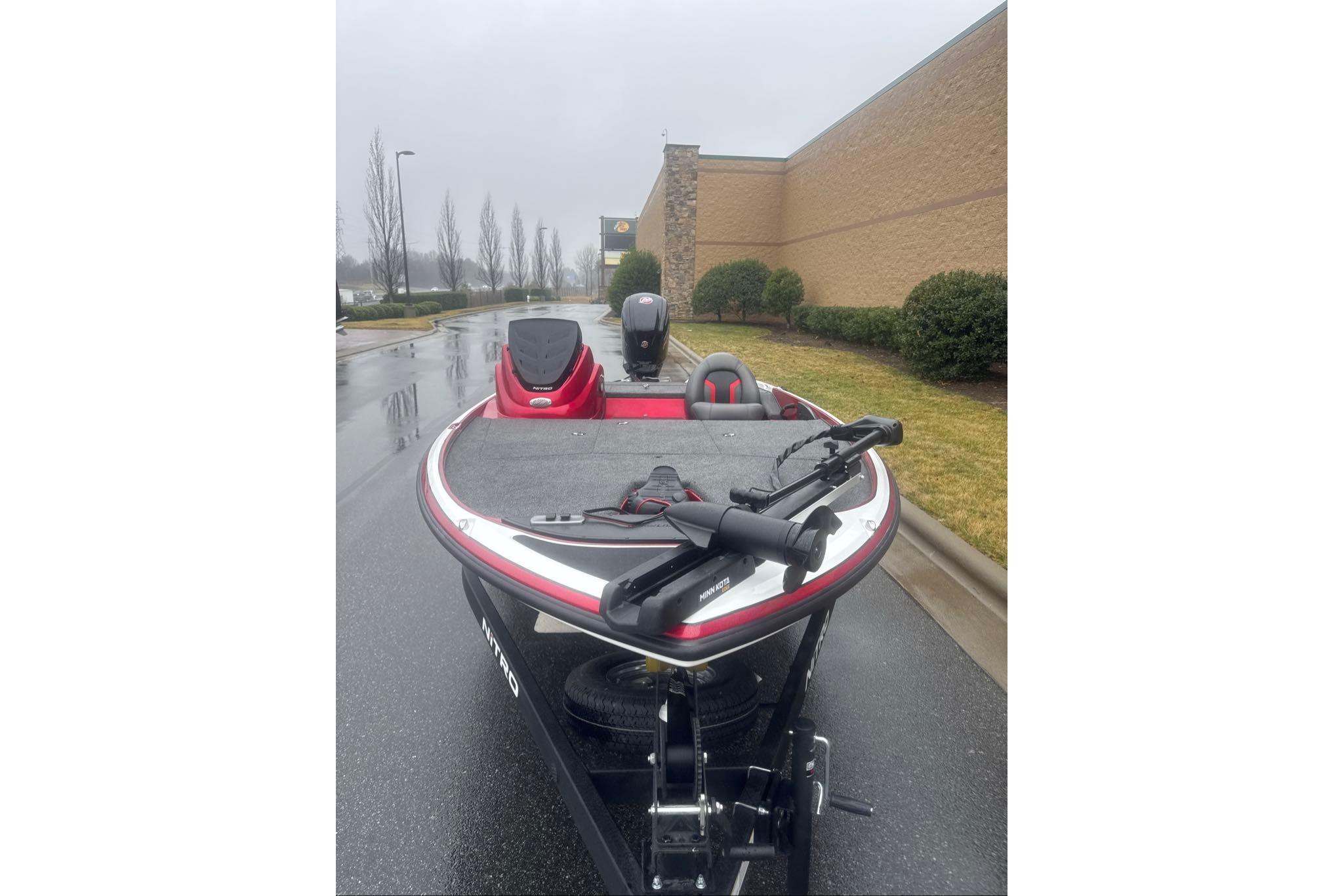 Red Nitro Z17 boat, 2026 model, parked on wet pavement near a building.