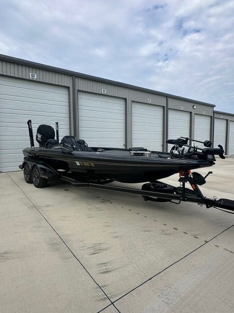 A 2023 Skeeter FXR21 Apex boat on a trailer in front of garages.