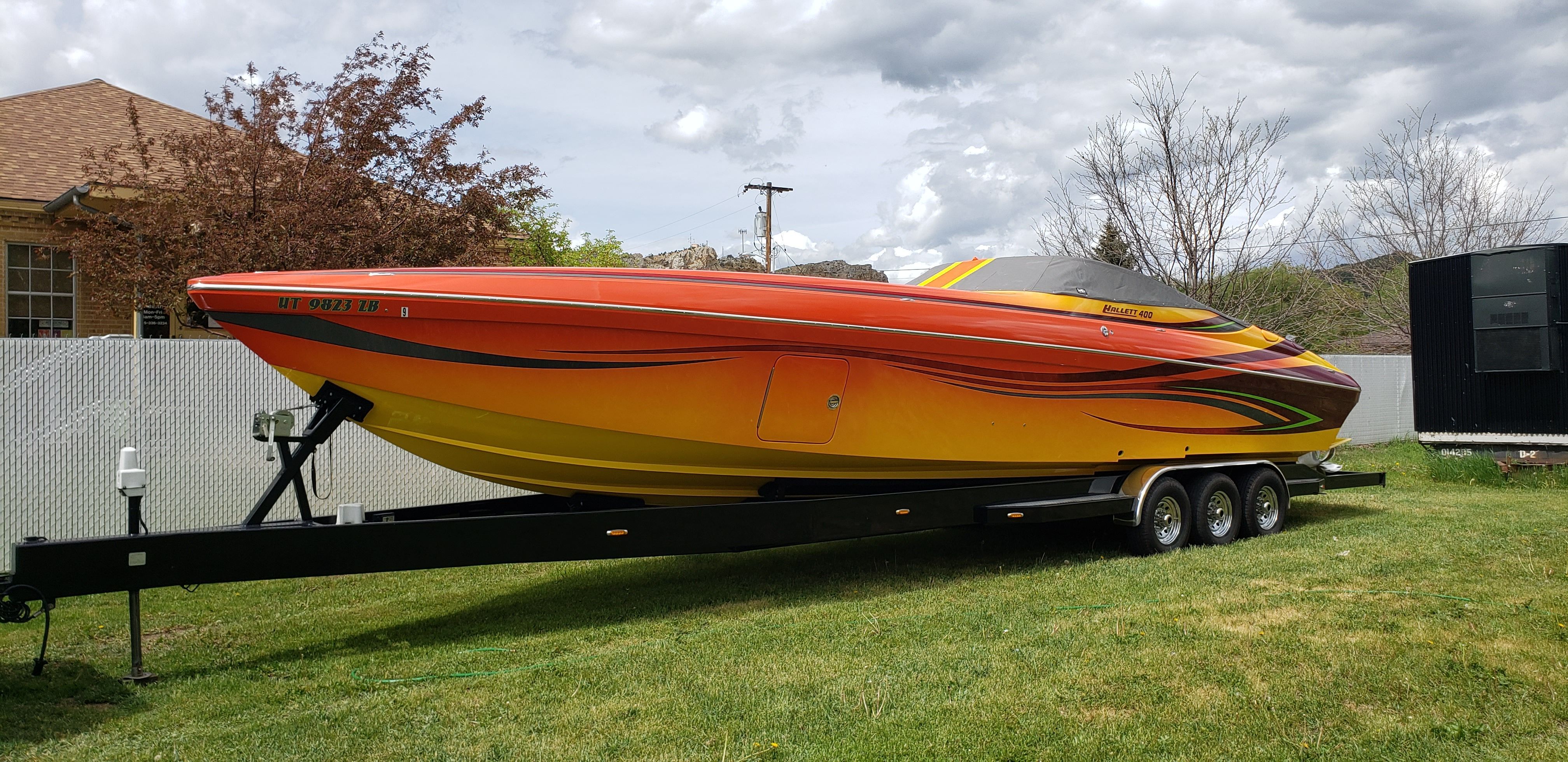 2009 Hallett 400T boat on trailer in a yard.