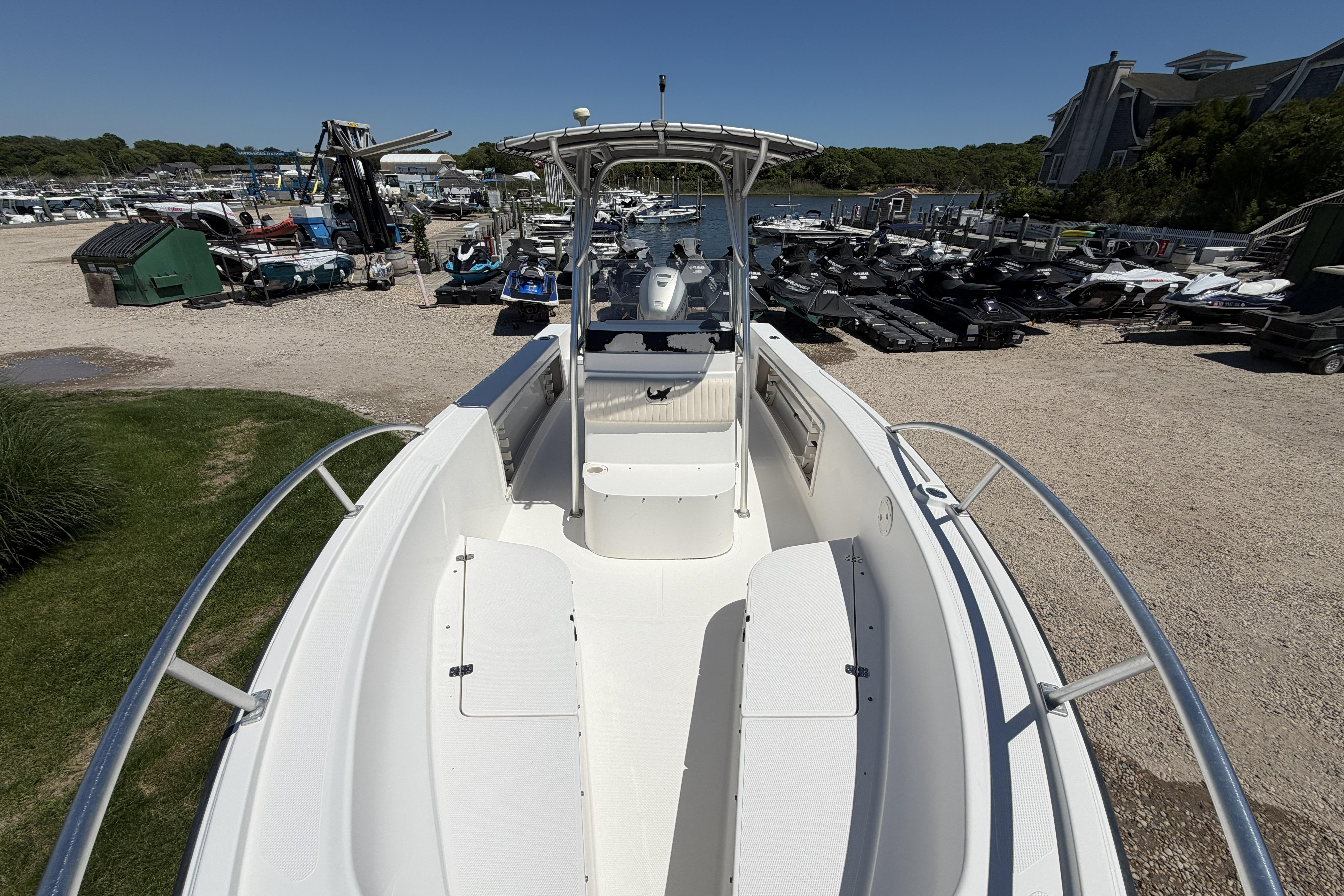 2006 Mako 212 Center Console boat docked, surrounded by other watercraft and greenery.