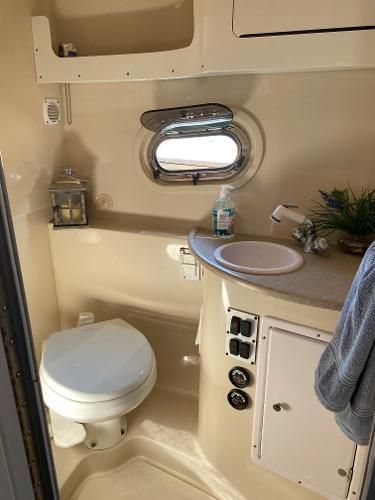 Interior of a boat cabin with a toilet, sink, and small window.