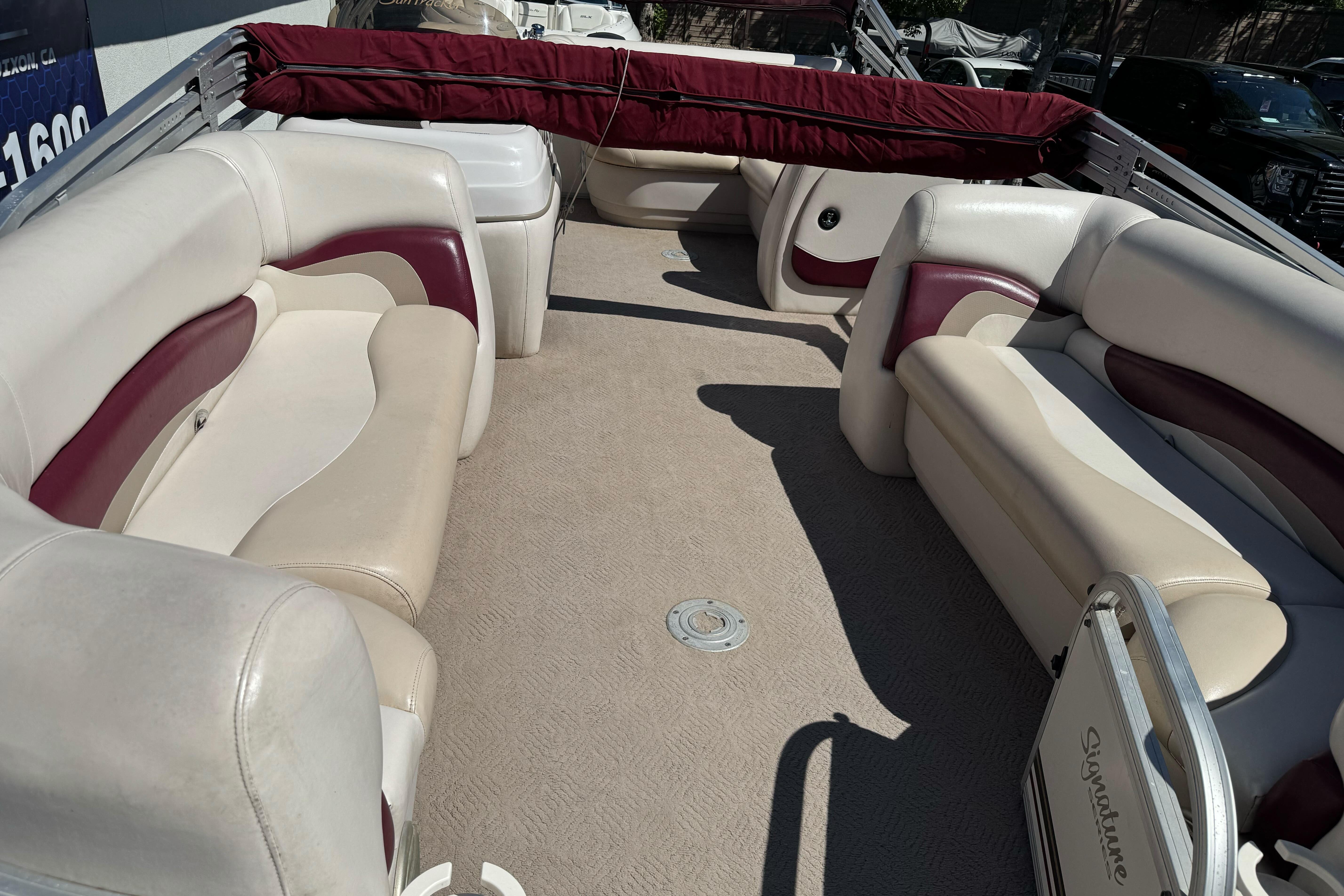 2011 Sun Tracker Party Barge 21 interior with beige and maroon seating, spacious layout.