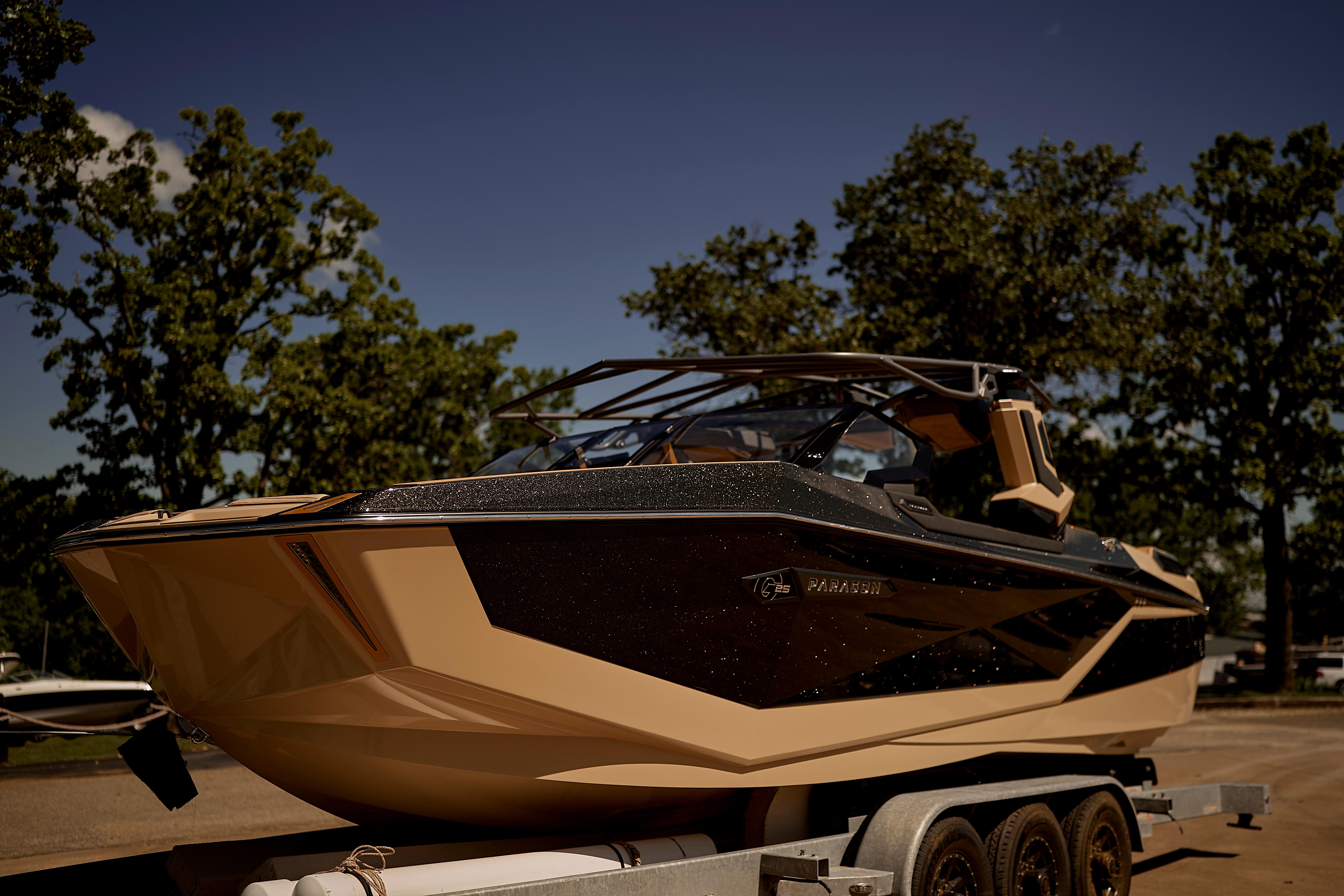 2025 Nautique Super Air Nautique G25 Paragon boat on trailer, surrounded by trees.