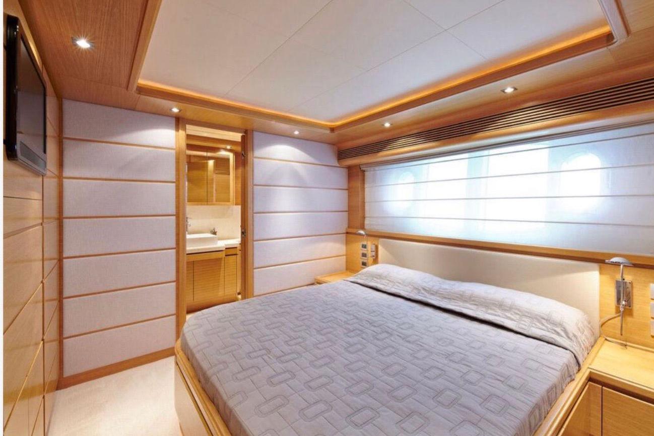 Luxurious bedroom interior on a 2010 Custom Line 97 yacht, featuring modern design and ambient lighting.