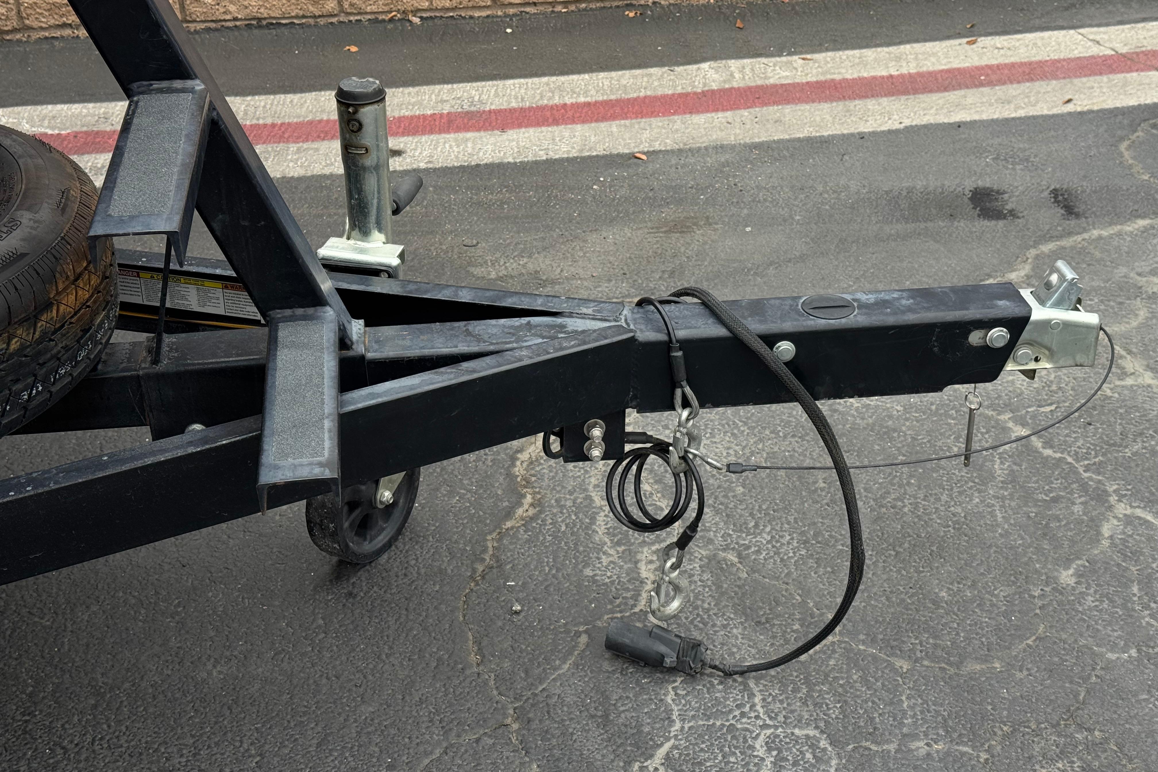 Trailer hitch and spare tire of a 2020 Manitou 18 Aurora LE on asphalt.