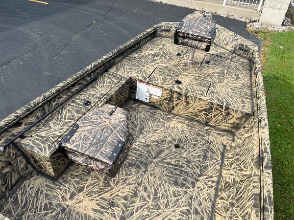2024 Lowe Roughneck 1660 camo boat interior with seating and storage compartments.