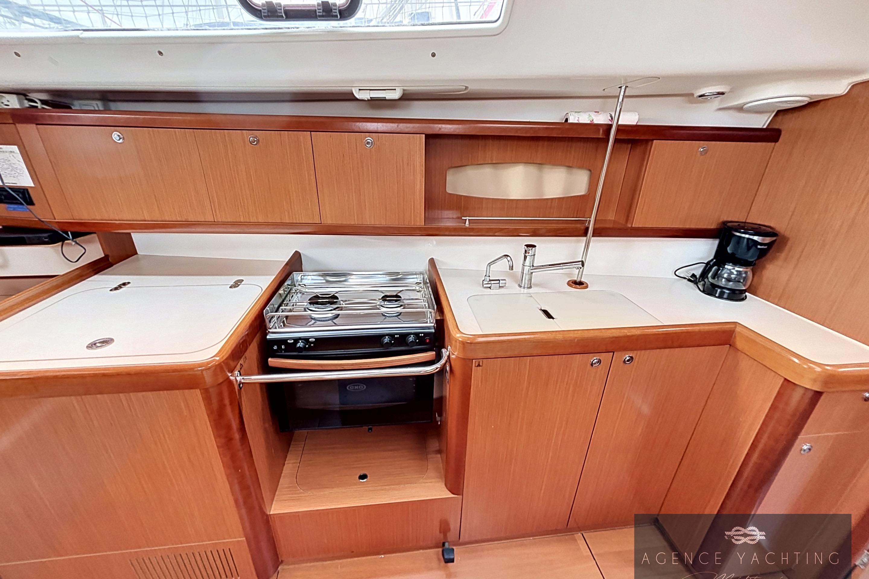 Interior of 2008 Beneteau Oceanis 40 yacht kitchen with stove, sink, and wooden cabinetry.