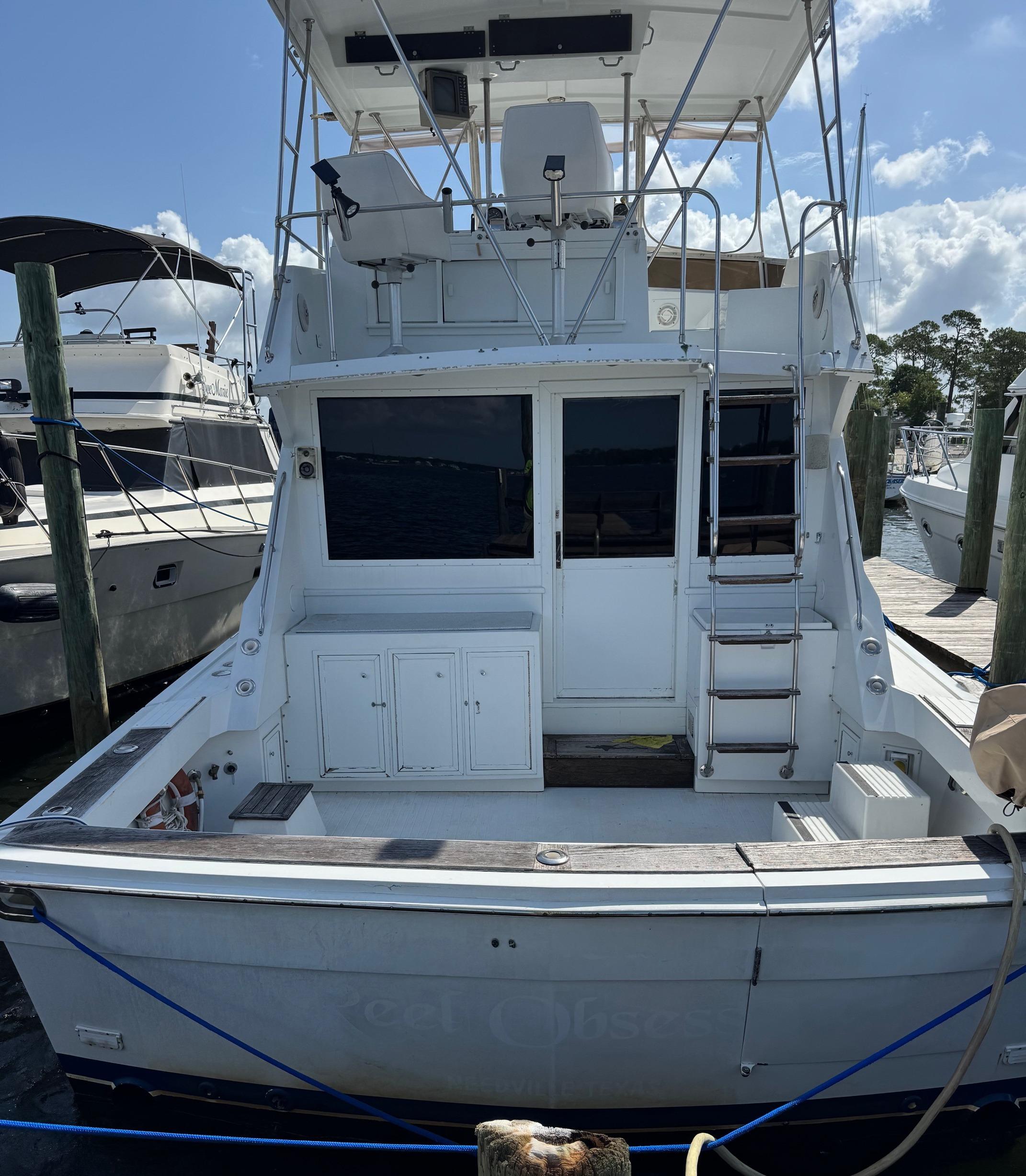 1982 Viking 46 Convertible yacht docked at marina, rear view with ladder and seating area.
