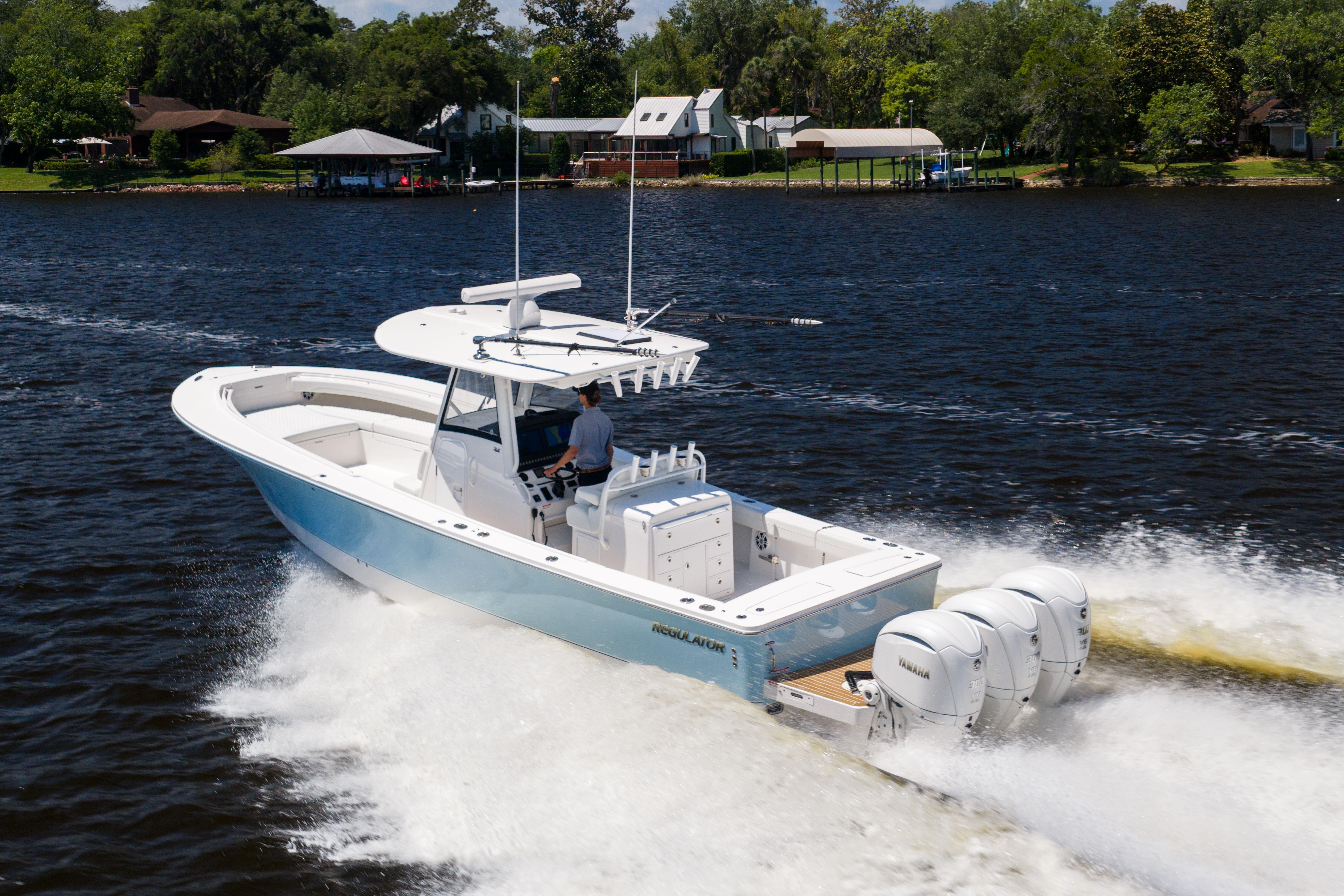 2024 Regulator 34 boat cruising on a lake with triple outboard engines.