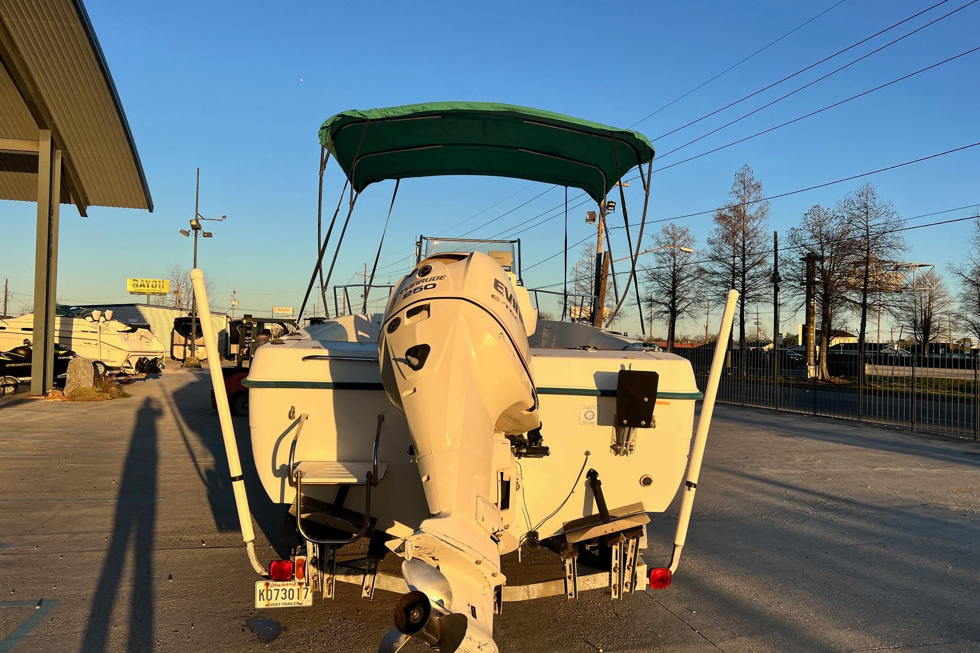 1998 Sunbird 230 CC boat with Evinrude motor, parked outdoors under a clear sky.