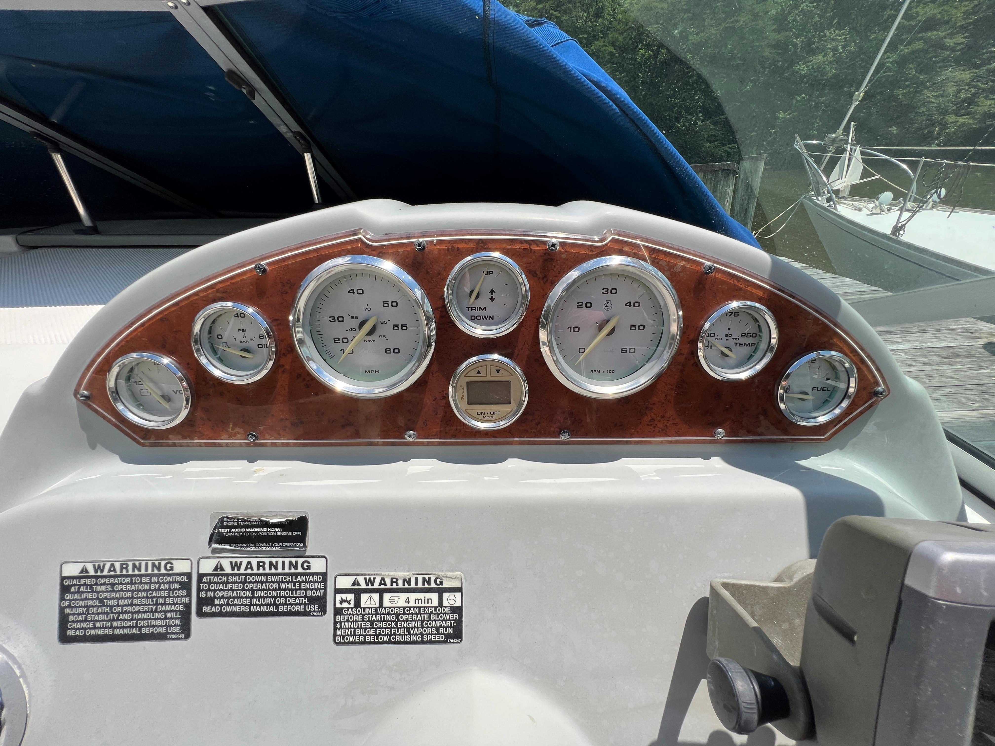 Dashboard of a 2007 Bayliner 265 boat with gauges and warning labels.