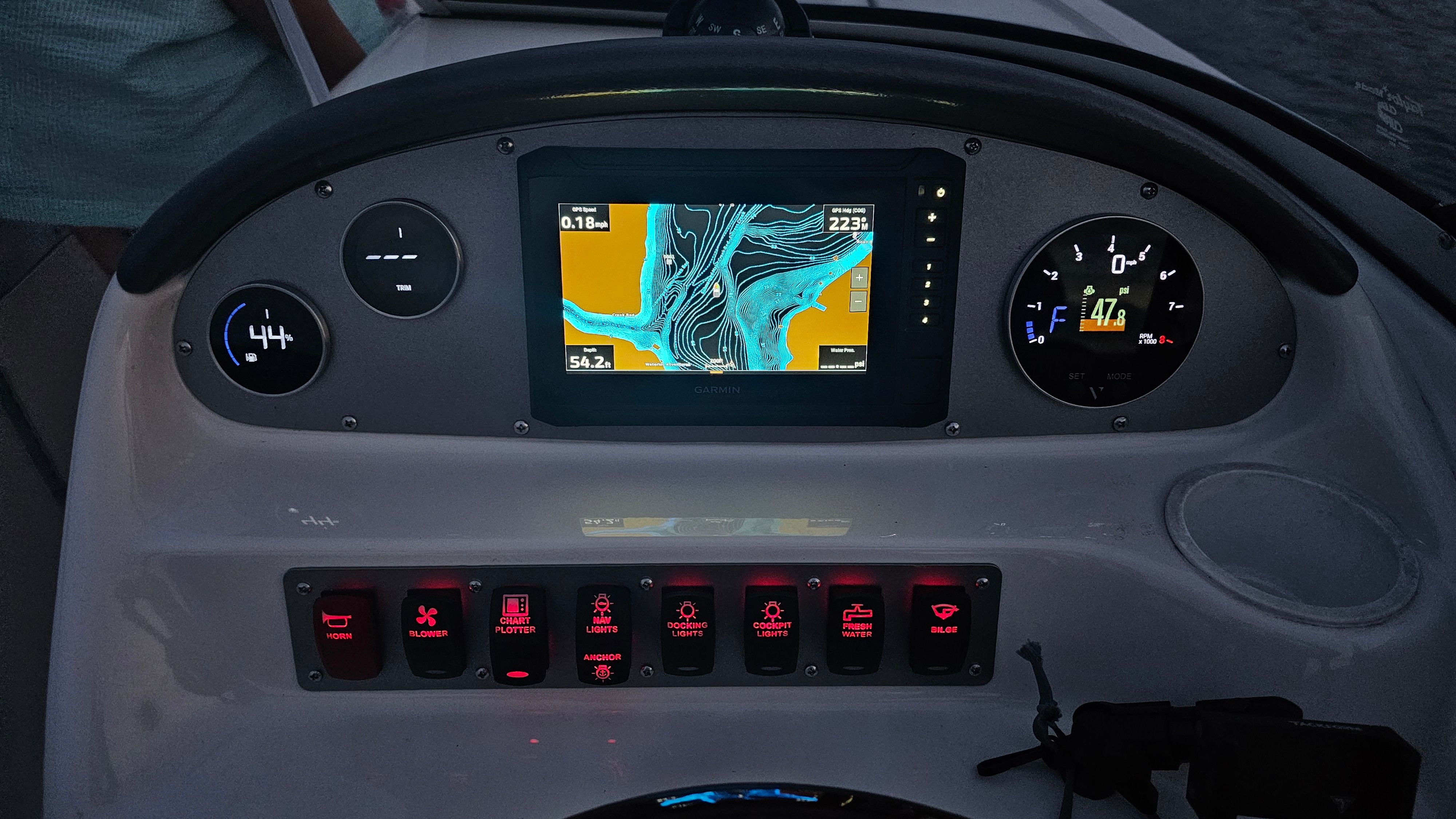 The dashboard of a boat with a navigation screen and various instruments.