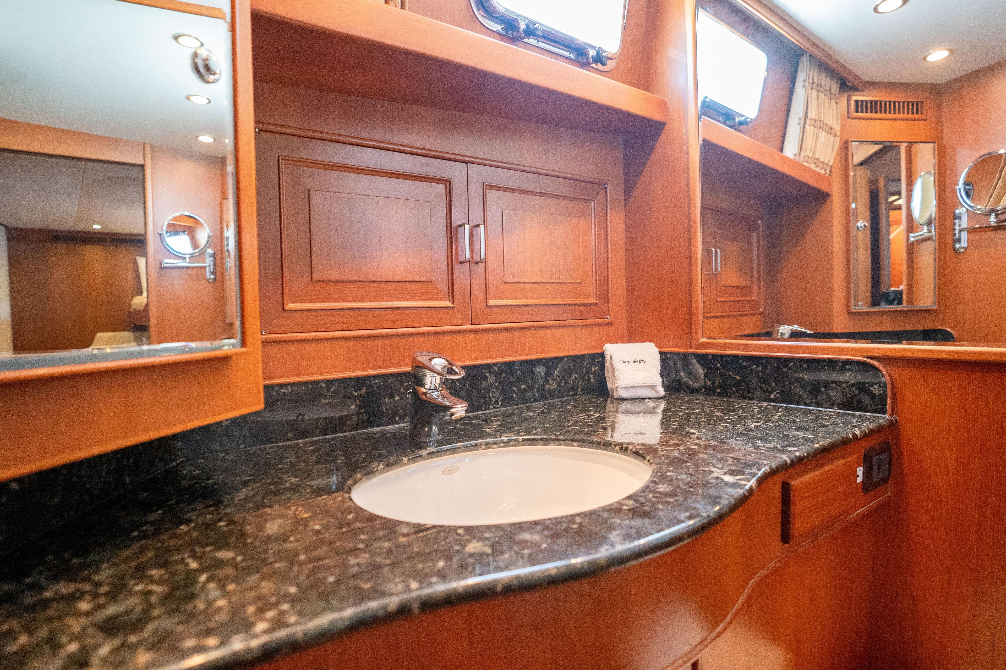 Luxurious bathroom interior on a 2006 Fleming 75 yacht with wood cabinetry and marble countertop.
