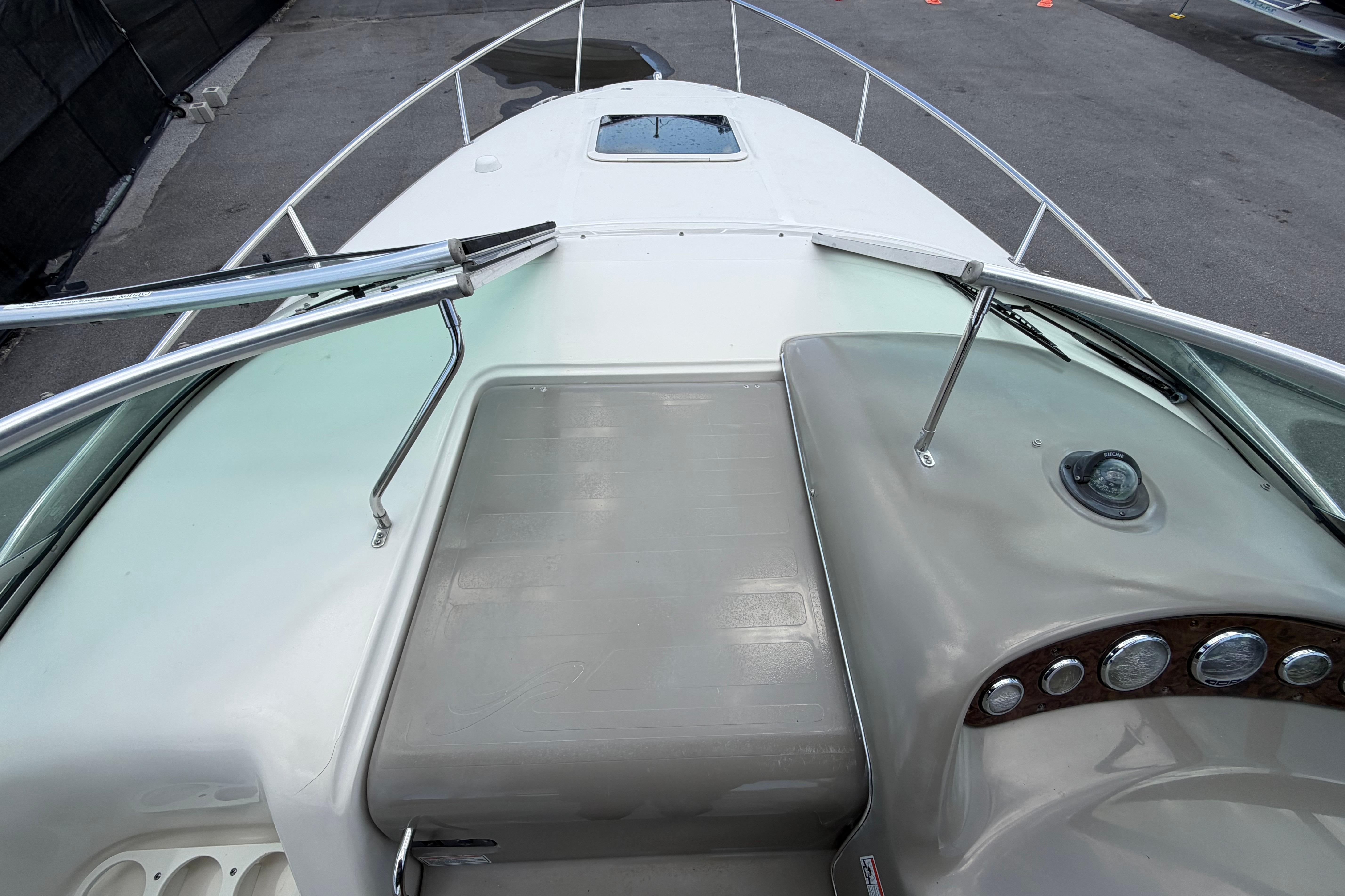 2006 Sea Ray 250 Amberjack boat deck with windshield and railing, docked on pavement.