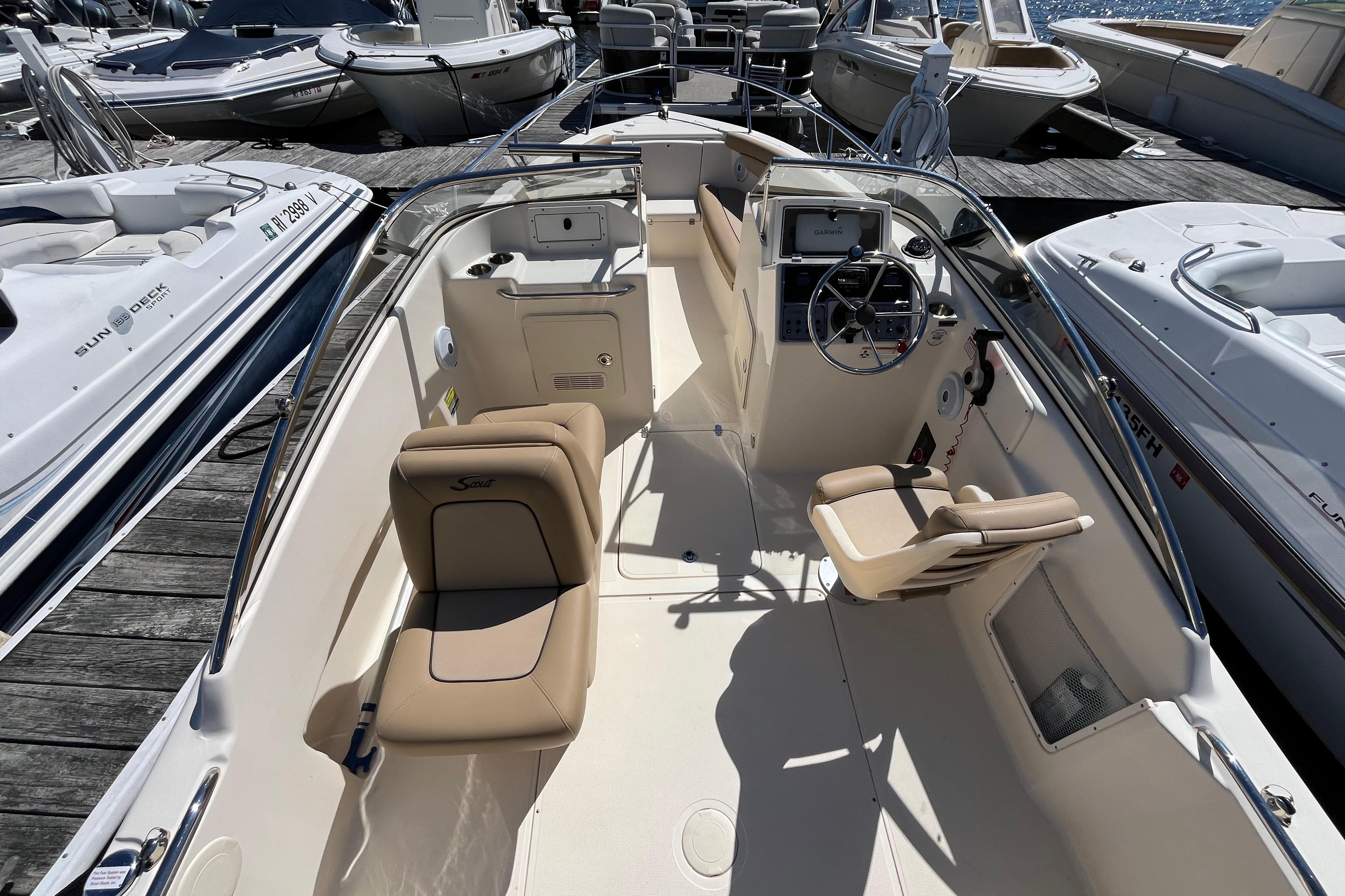 2017 Scout 210 Dorado boat interior with beige seating and steering console at a marina.