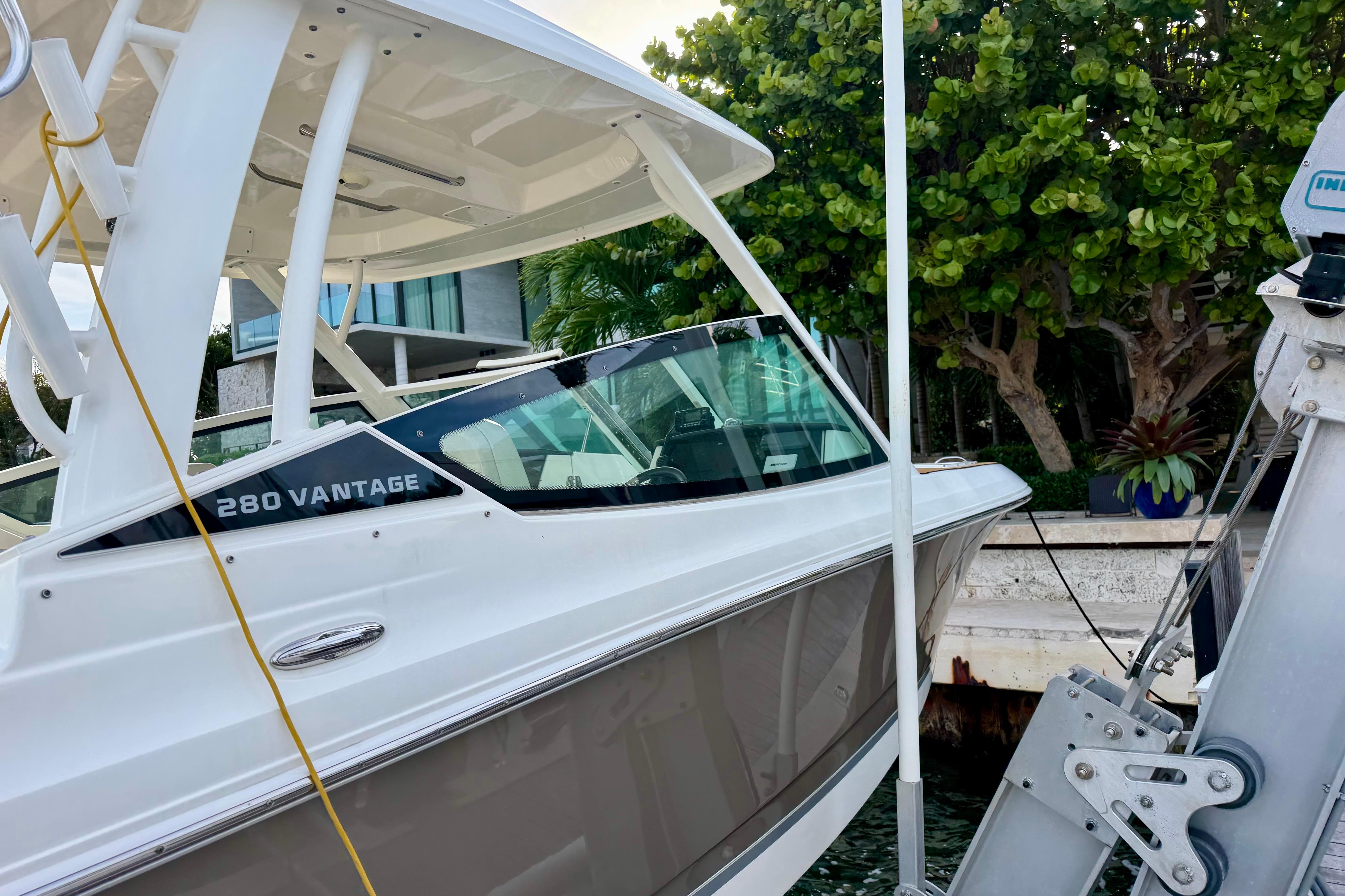 2022 Boston Whaler 280 Vantage boat docked near lush greenery.