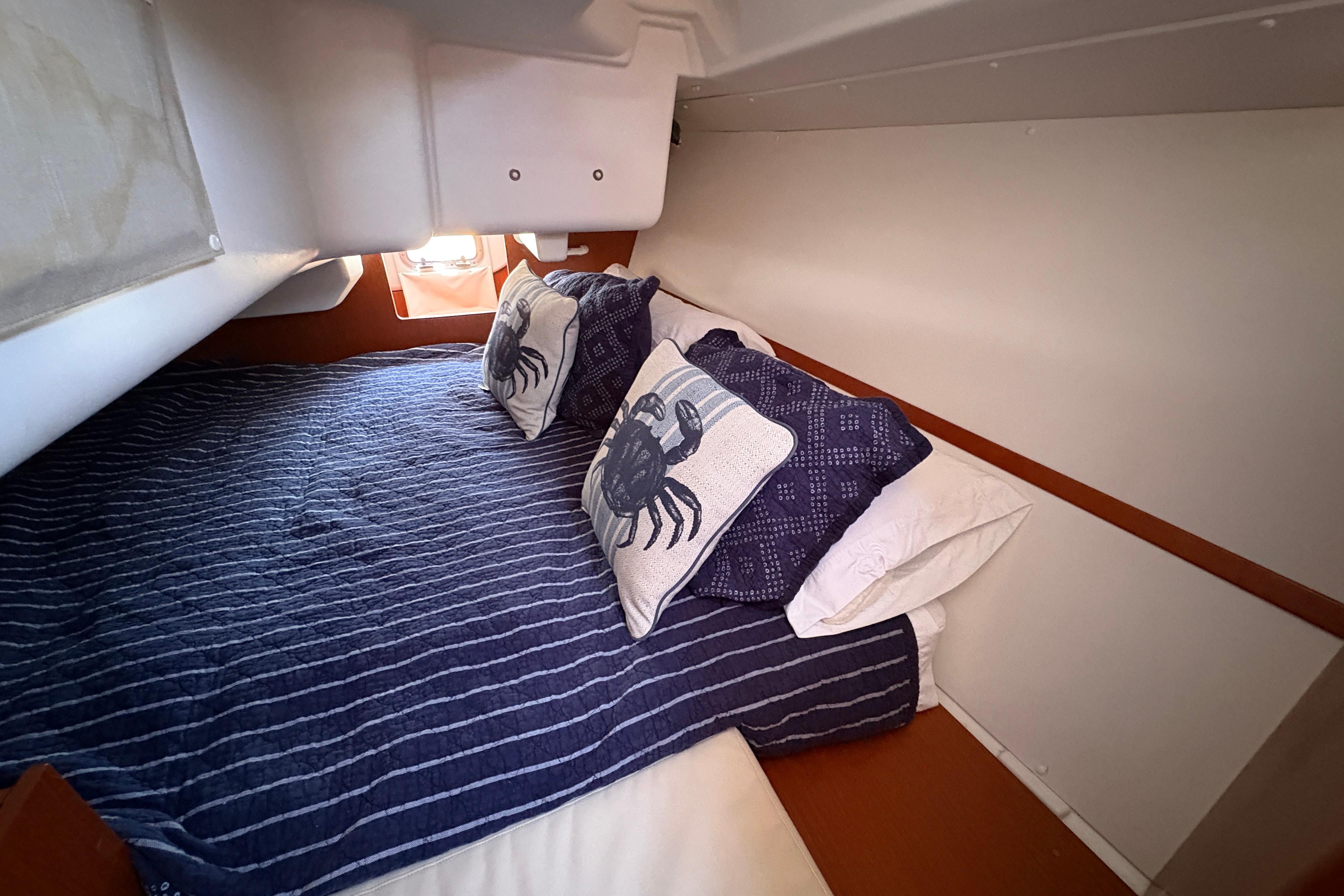 Cozy cabin interior of 2015 Beneteau Oceanis 34 with nautical-themed bedding.