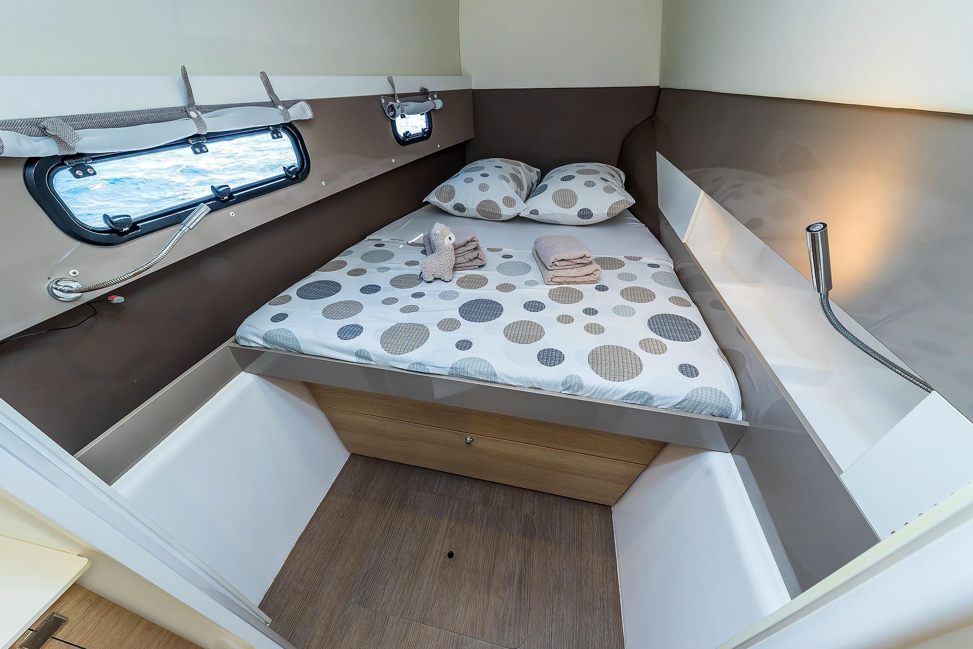 Cozy cabin interior of 2018 Bali 4.1 yacht with polka dot bedding and porthole view.