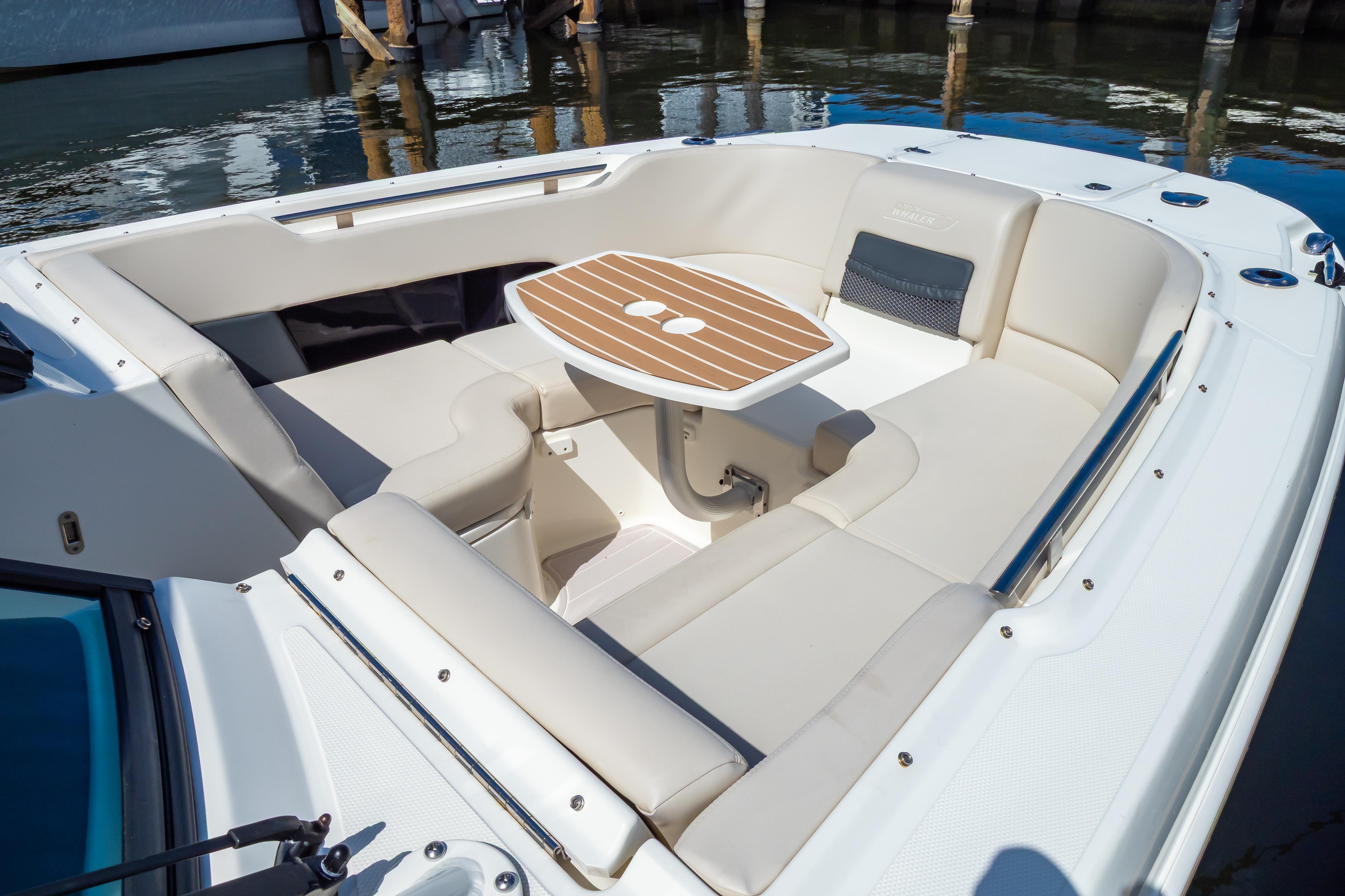 2019 Boston Whaler 270 Vantage boat interior with cushioned seating and wooden table.