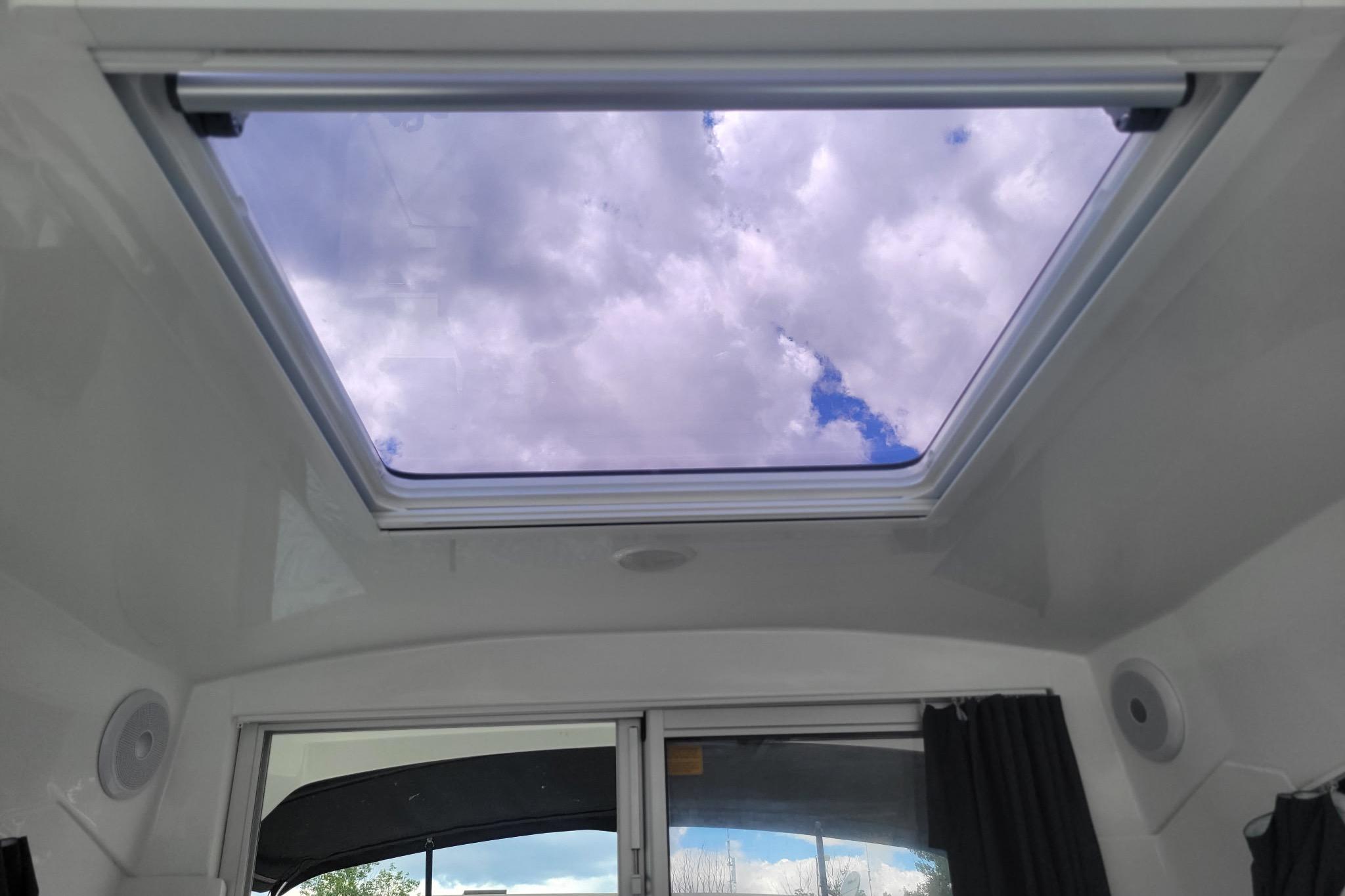Skylight view from 2019 Beneteau Antares 23, showcasing cloudy sky through cabin window.