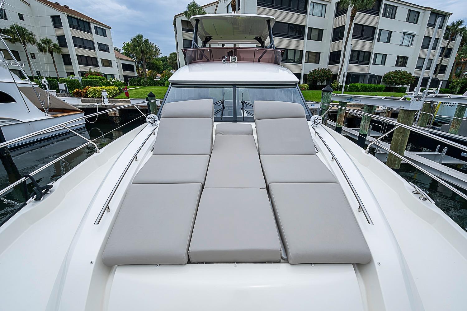 Prestige 520 yacht, 2021 model, with sun loungers docked near waterfront apartments.