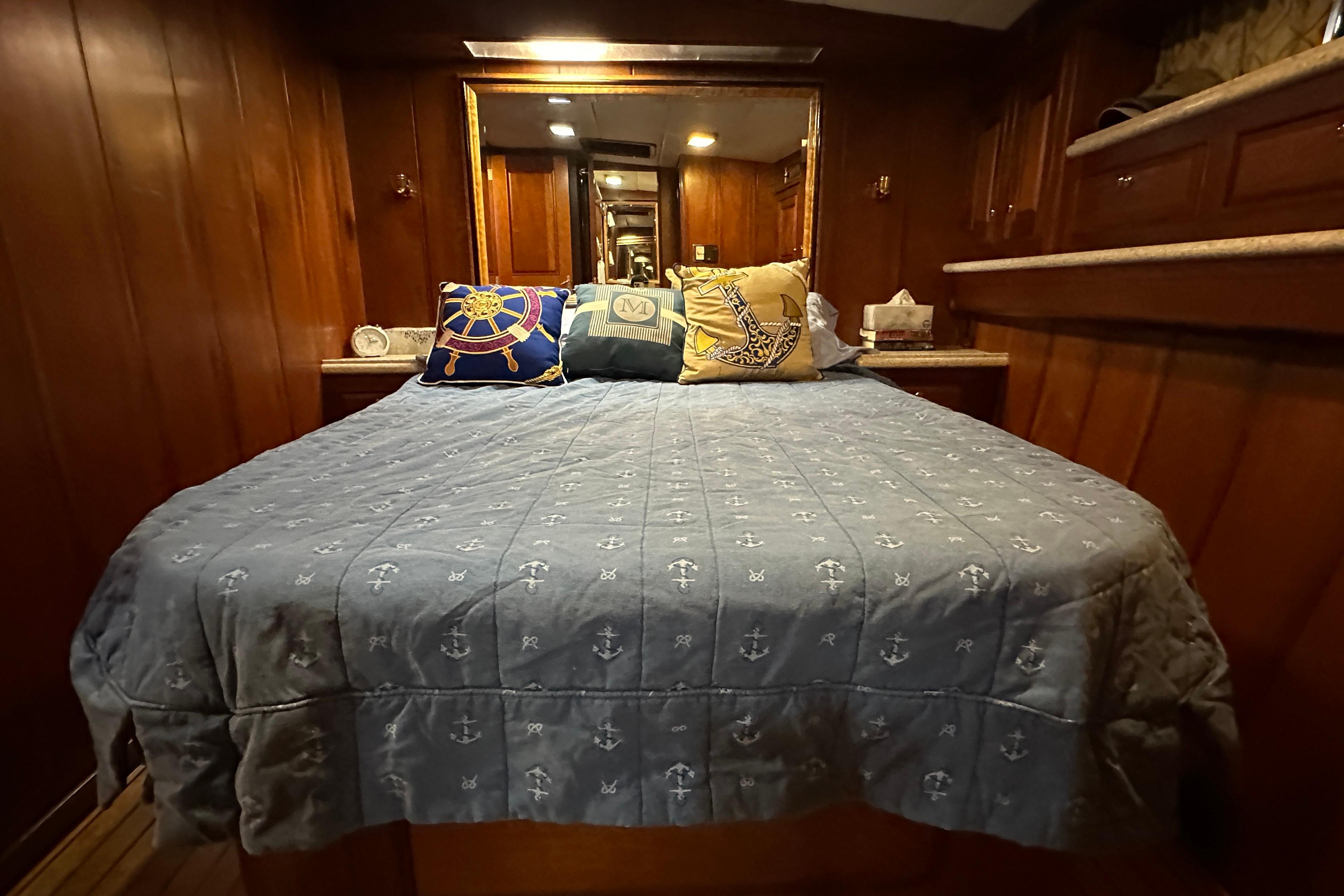 Cozy bedroom interior of 1980 Bertram 58 Convertible yacht with nautical-themed bedding.