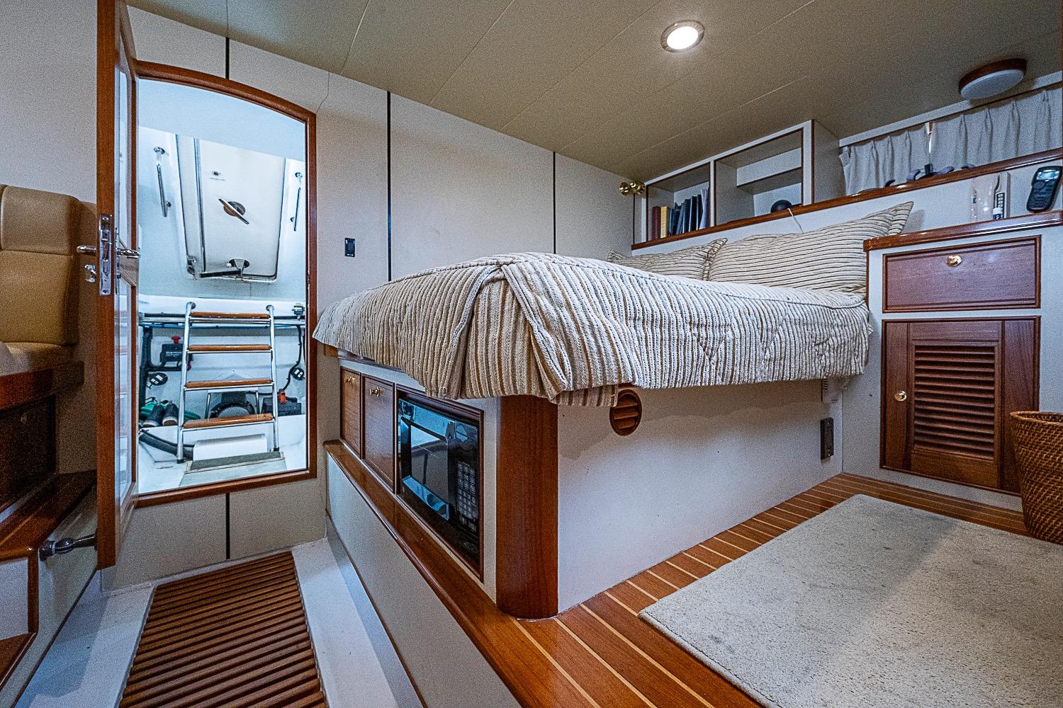Luxurious cabin interior of 2014 Marlow 80 Explorer yacht with cozy bed and wooden accents.