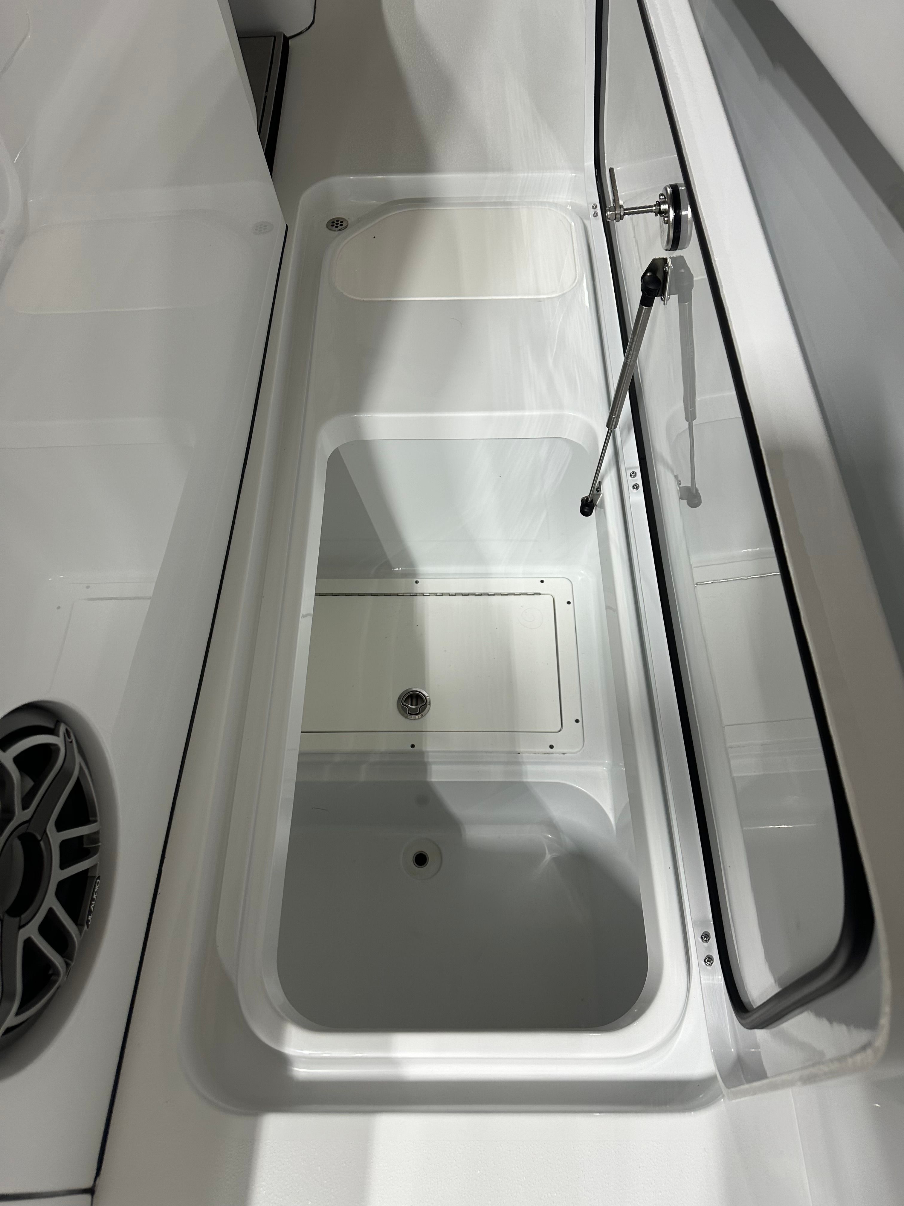 An open storage compartment on a boat with a speaker nearby.