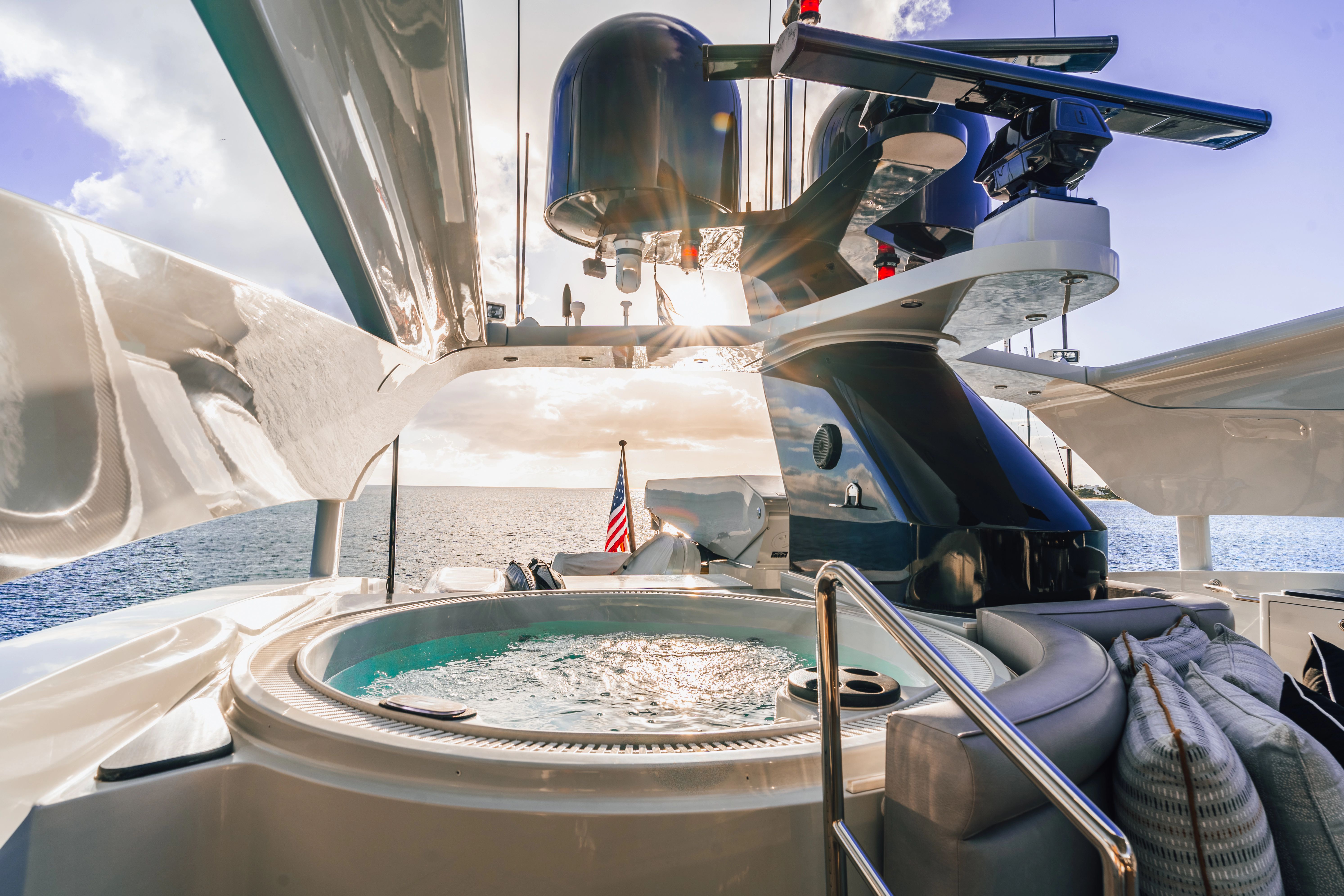 Luxurious yacht with a hot tub on deck, surrounded by calm sea and blue sky.