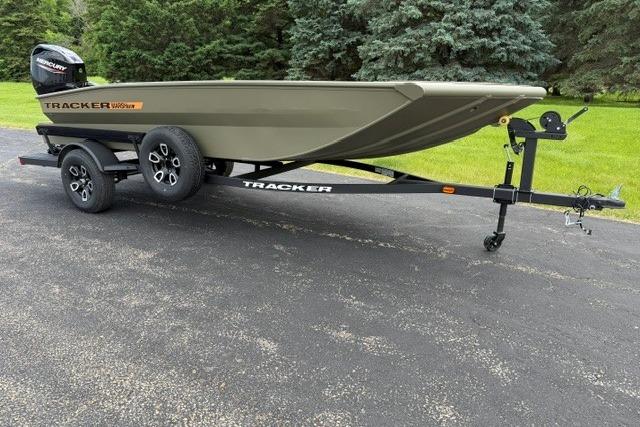 2026 Tracker Grizzly 1756 T Marsh boat on trailer, parked on asphalt with green trees in background.