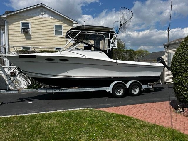 A 1998 Sport-Craft 252 Sport Fish boat on a trailer in front of a house.