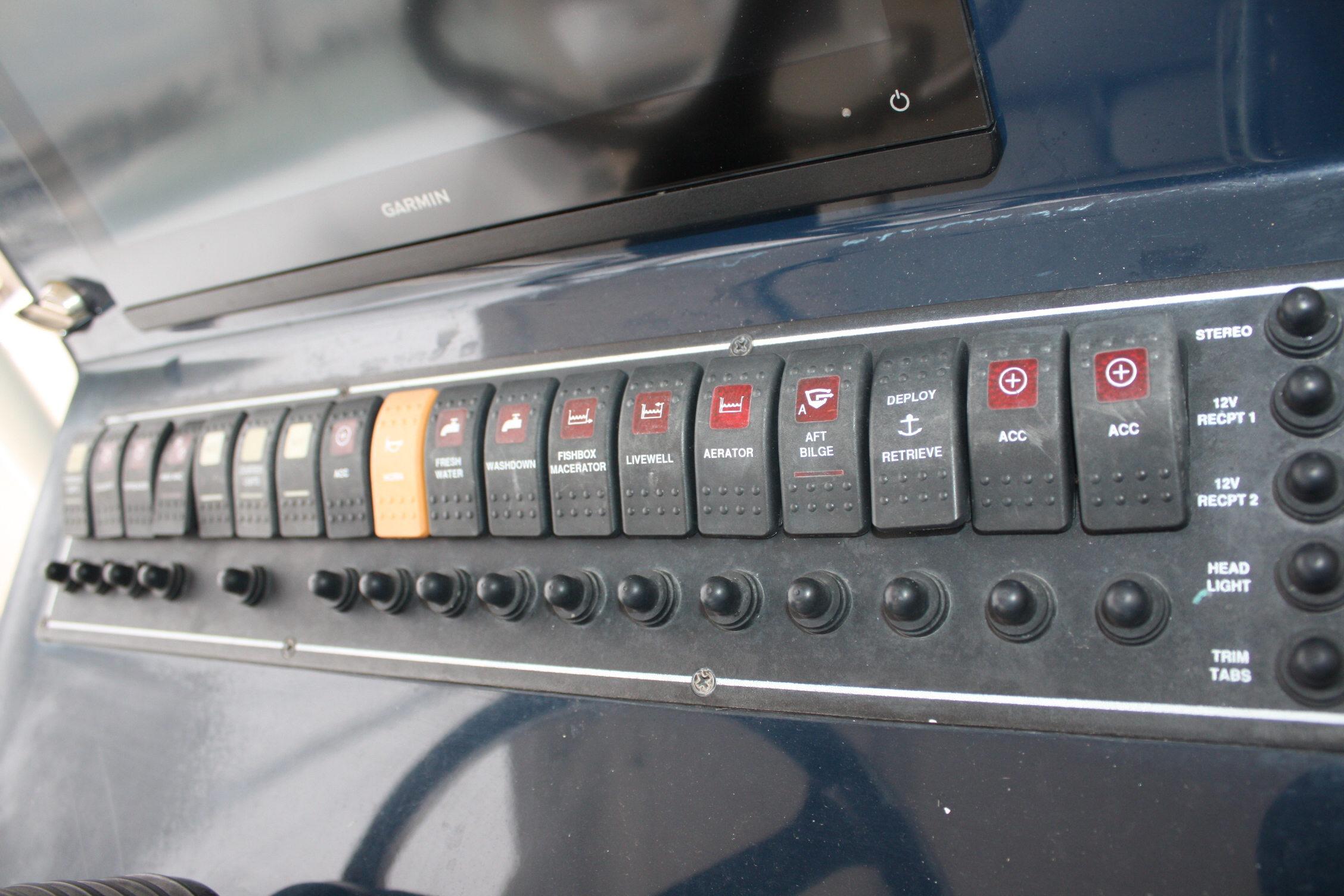 Control panel of a 2013 Pursuit ST 310 Sport boat with various switches and buttons.