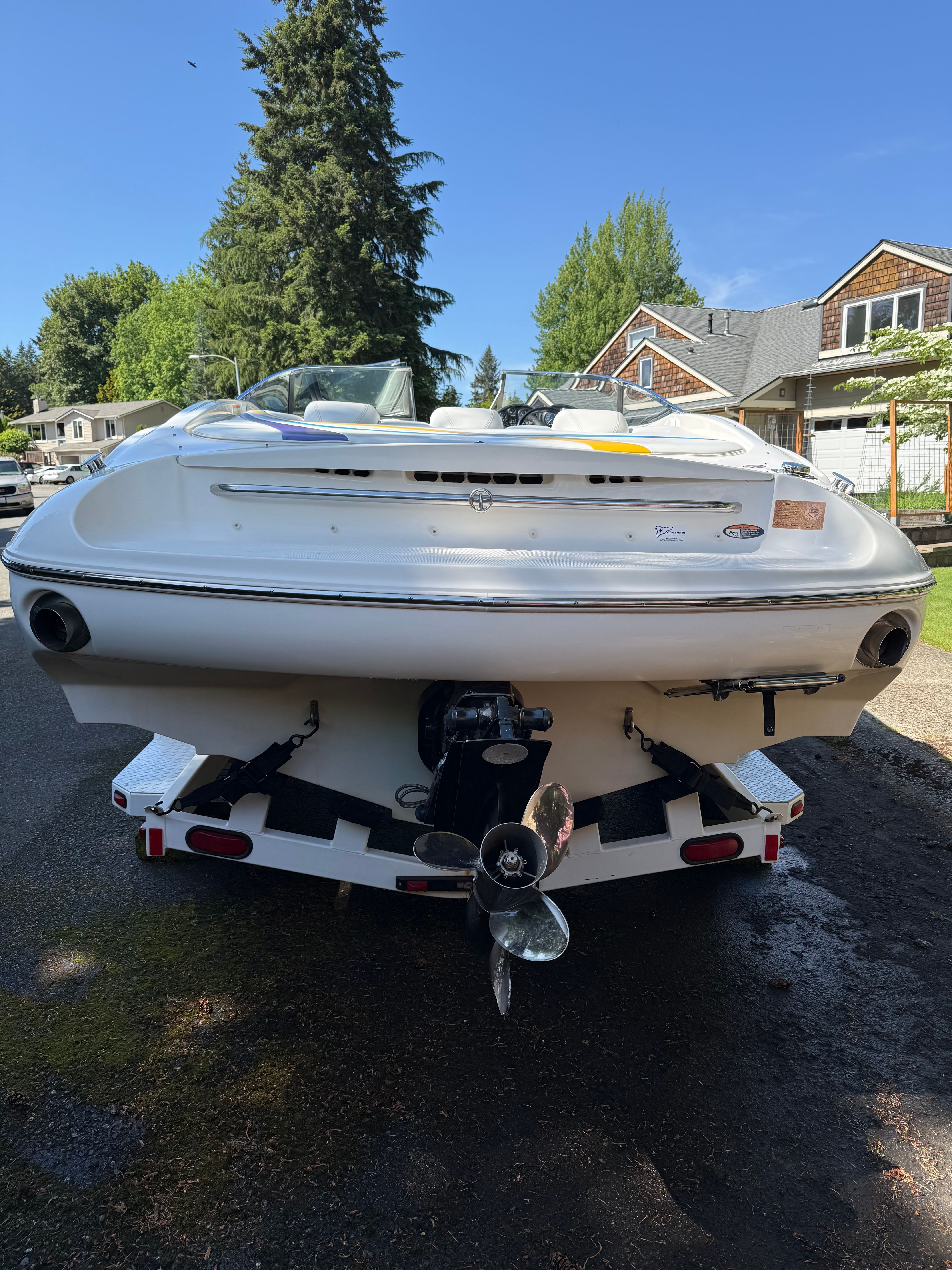 A white motorboat on a trailer in a residential area.