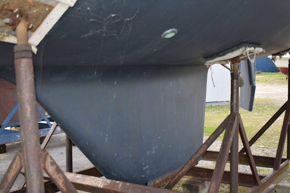 The hull of a 1987 S2 9.2A sailboat on a stand on land.