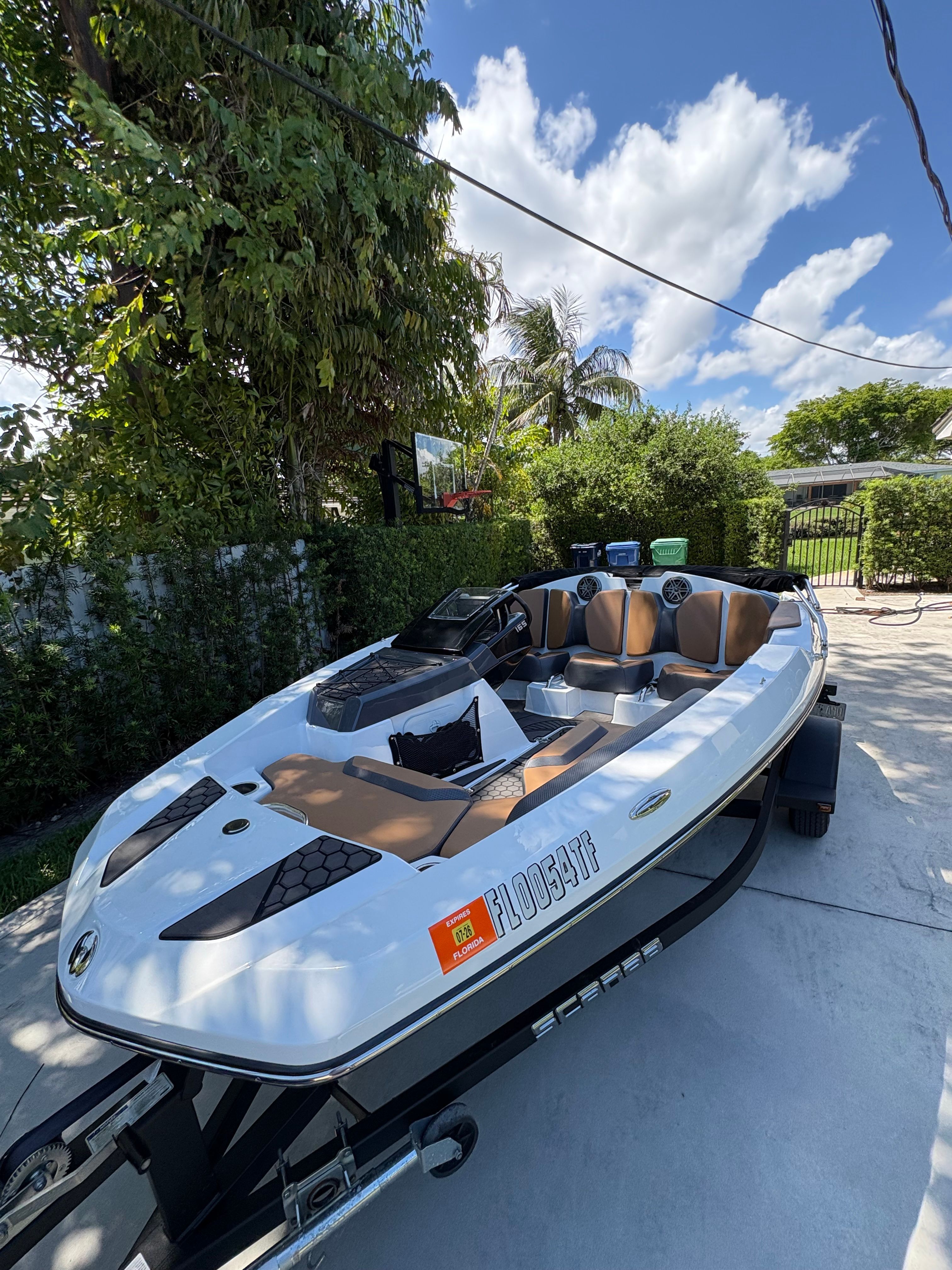 A white 2022 Scarab 165 ID boat on a trailer in a garden setting.