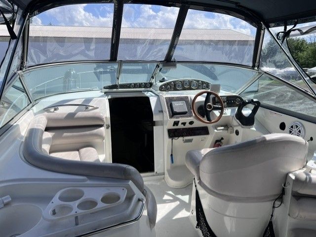 The cockpit of a 1999 Doral 300sc with white seating and a wooden steering wheel.