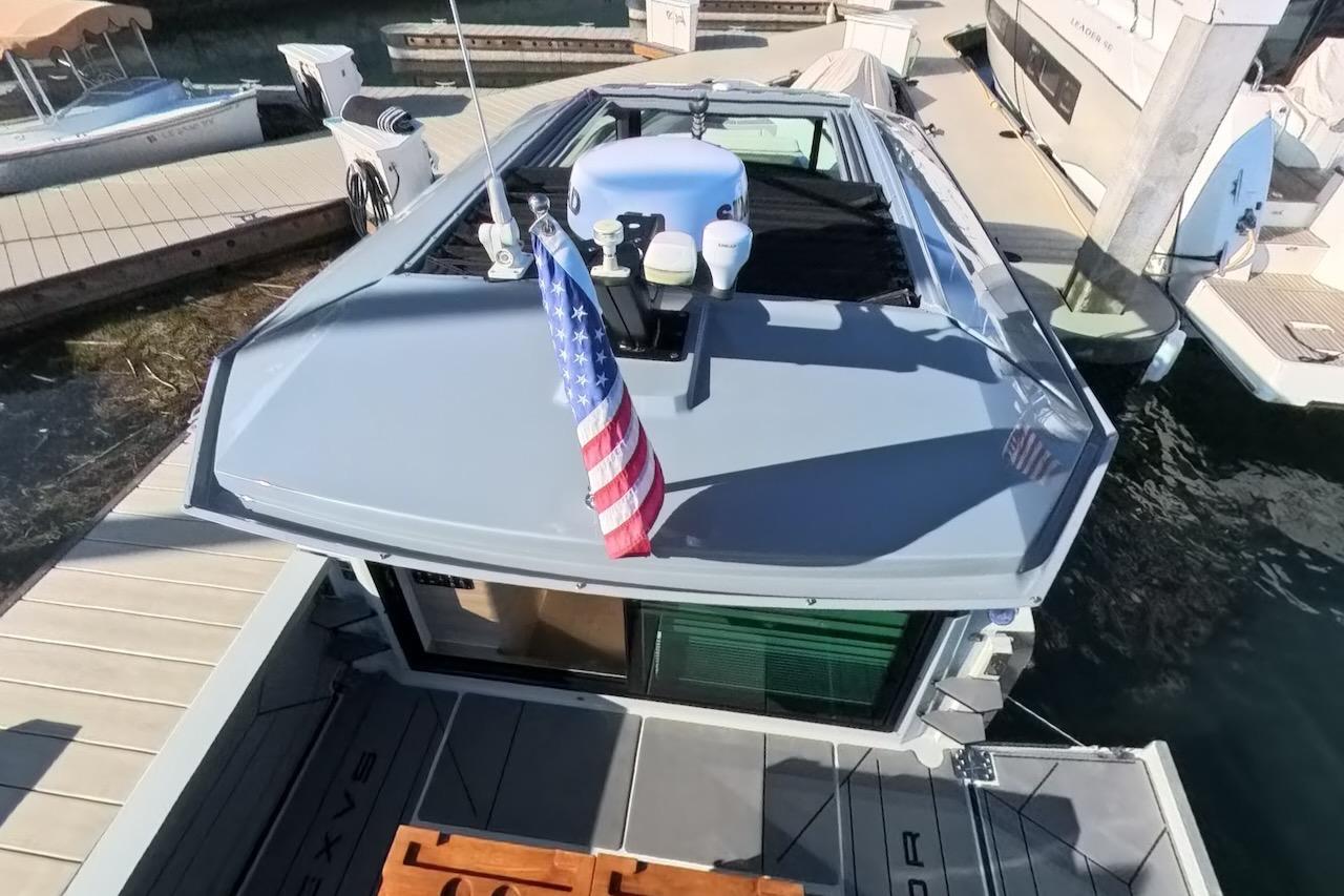 2024 Saxdor 320 GTC boat docked, featuring sleek design and American flag on deck.