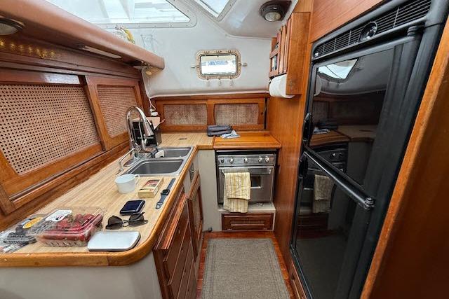 Interior of 1982 Lancer 45 Motorsailer kitchen with wooden cabinetry and modern appliances.