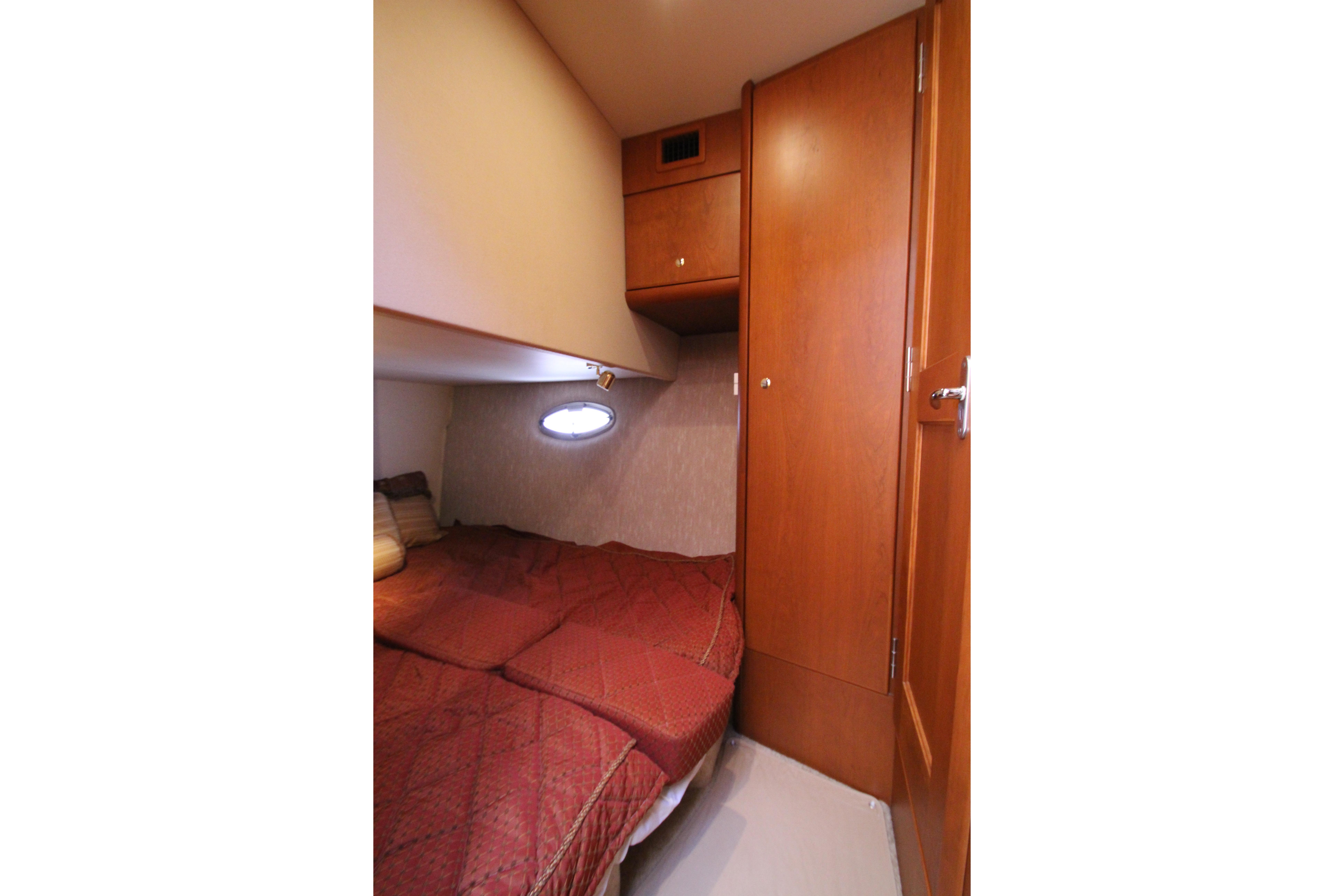 2006 Silverton 38 Sport Bridge cabin with cozy bed and wooden cabinetry.