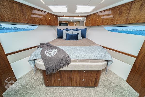 Luxurious bedroom interior of 2025 Riviera 645 SUV yacht with wooden finishes and ocean view.