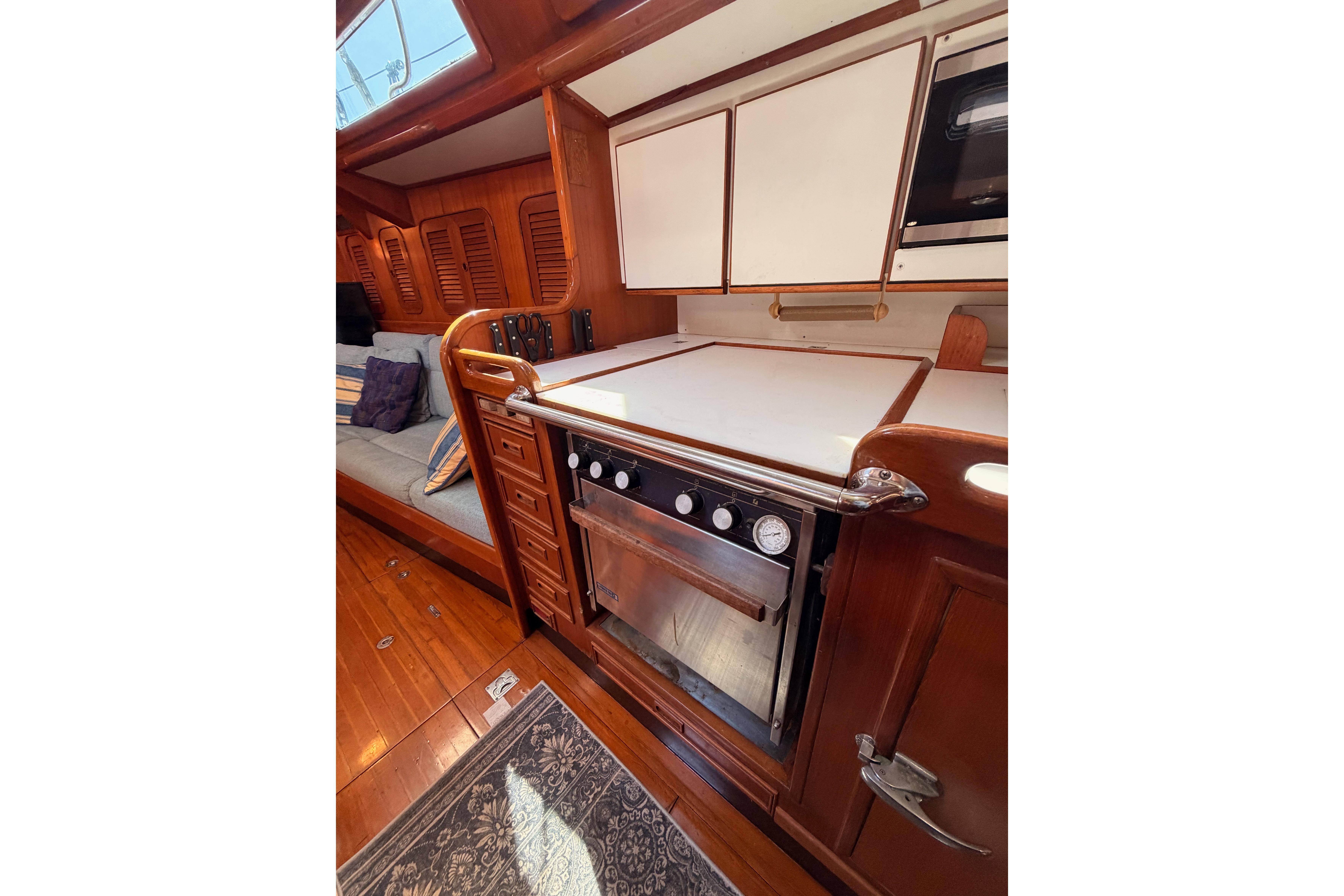 Interior of 1991 Hylas 51 yacht featuring a wooden galley with stove and seating area.