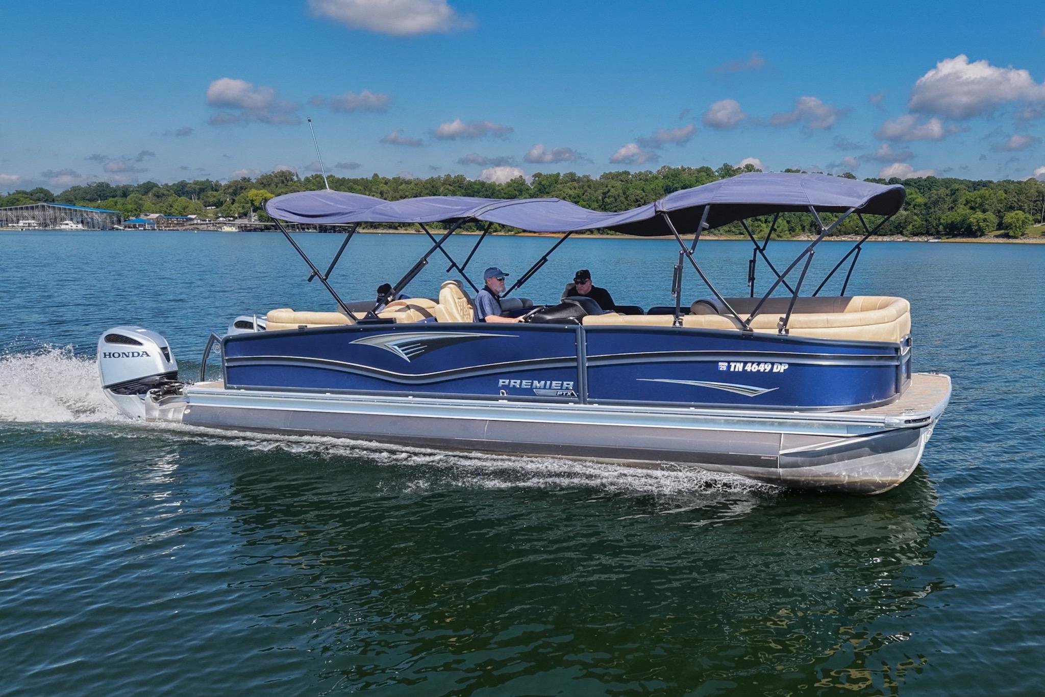 2023 Premier 270 Intrigue RF pontoon boat cruising on a lake under a clear blue sky.