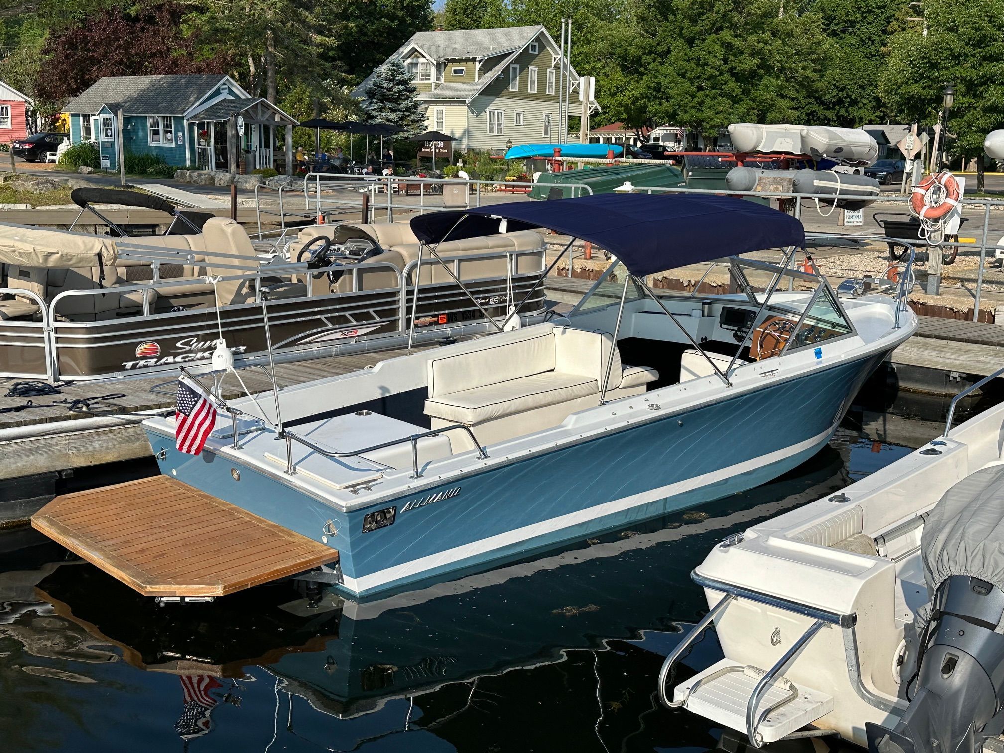 A 1969 John Allmand Citation II docked. It features a blue hull design and a sunshade.
