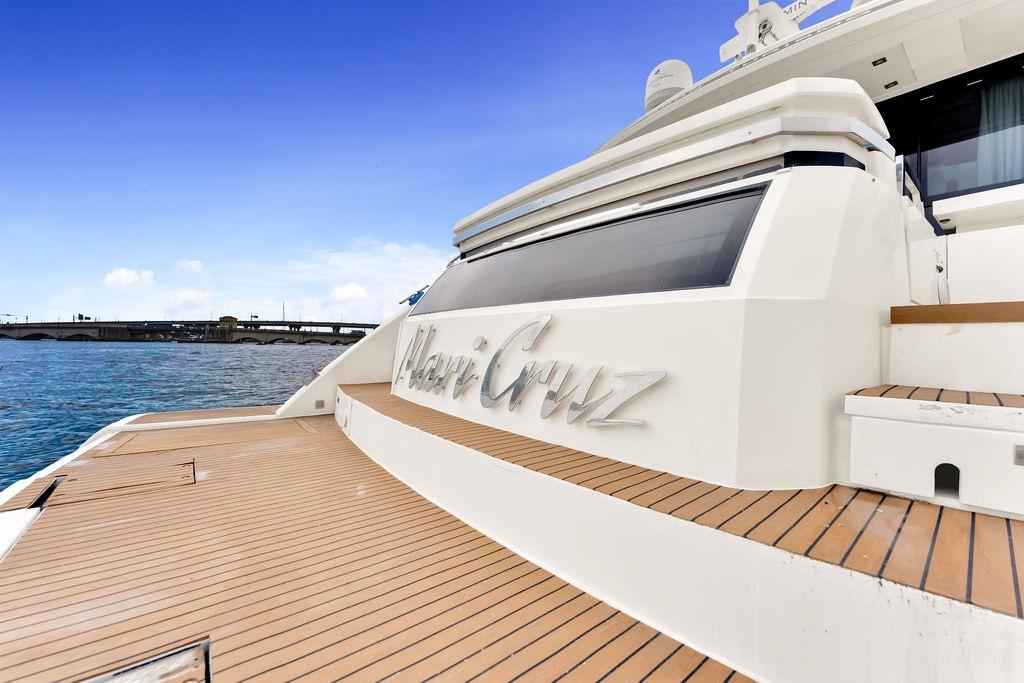 2012 Fairline Targa 58 yacht with teak deck, docked by a bridge under a clear blue sky.
