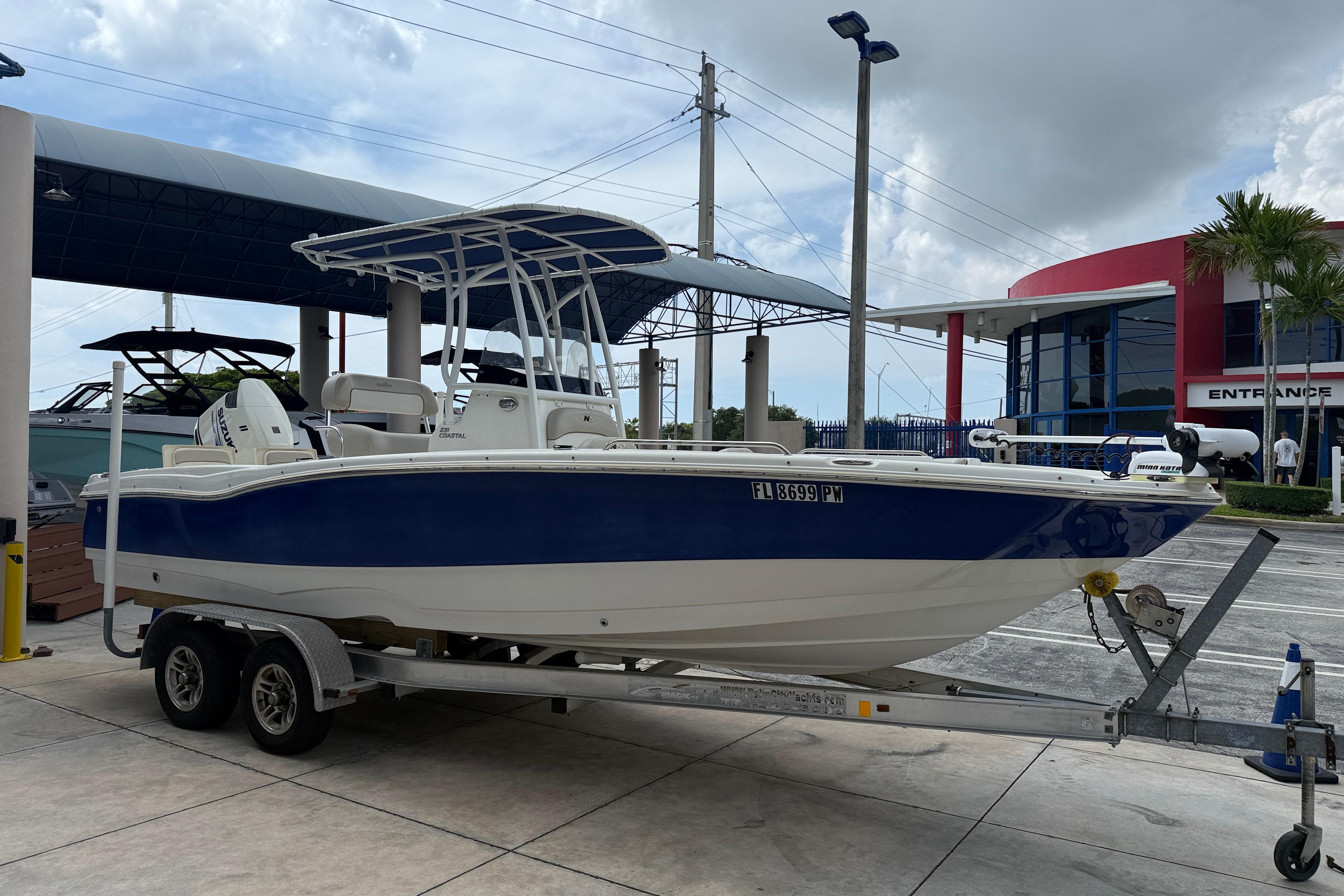 2015 NauticStar 231 Coastal boat on trailer at dealership, blue and white design.