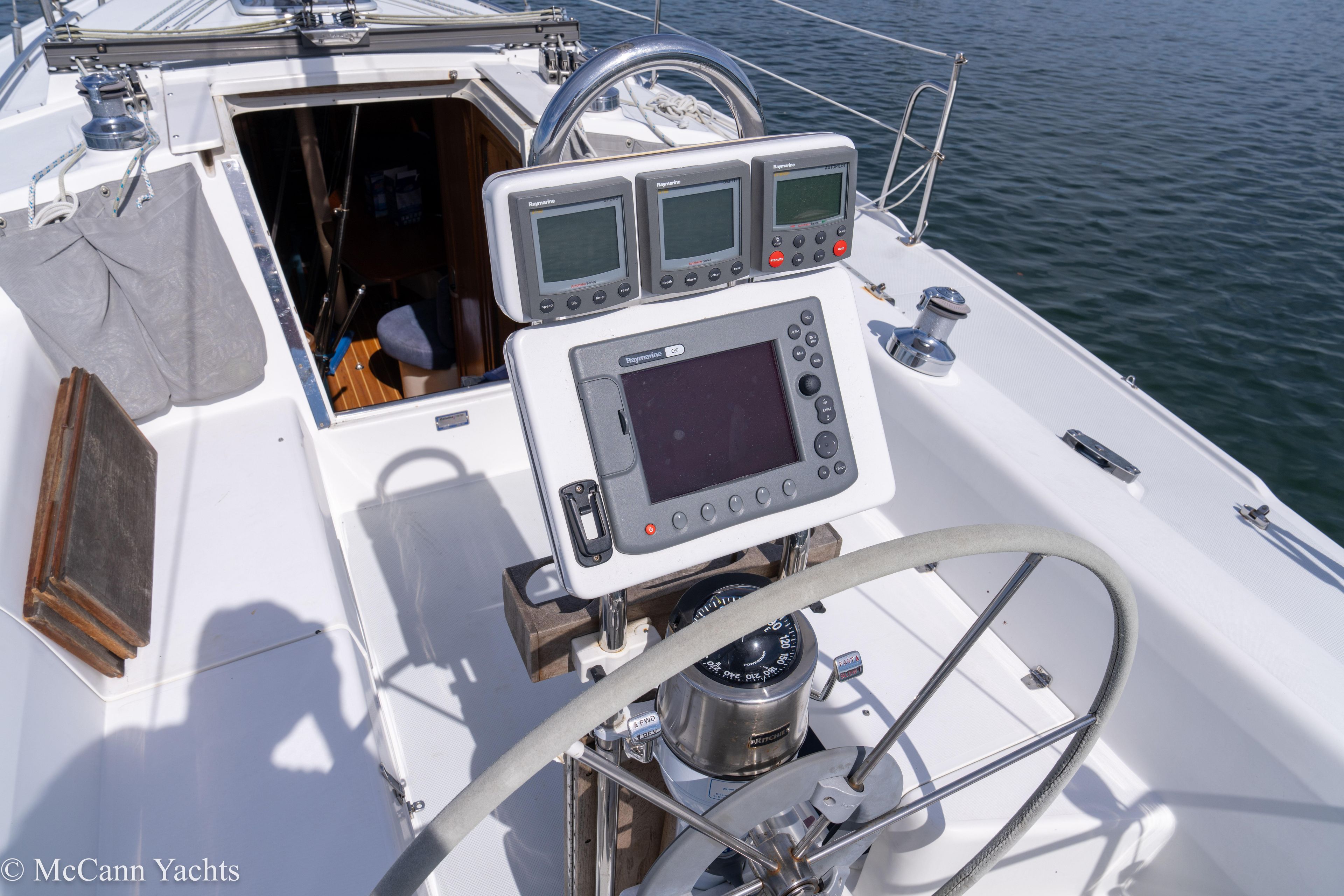 Cockpit of 2003 Catalina 320 sailboat with navigation instruments and steering wheel.