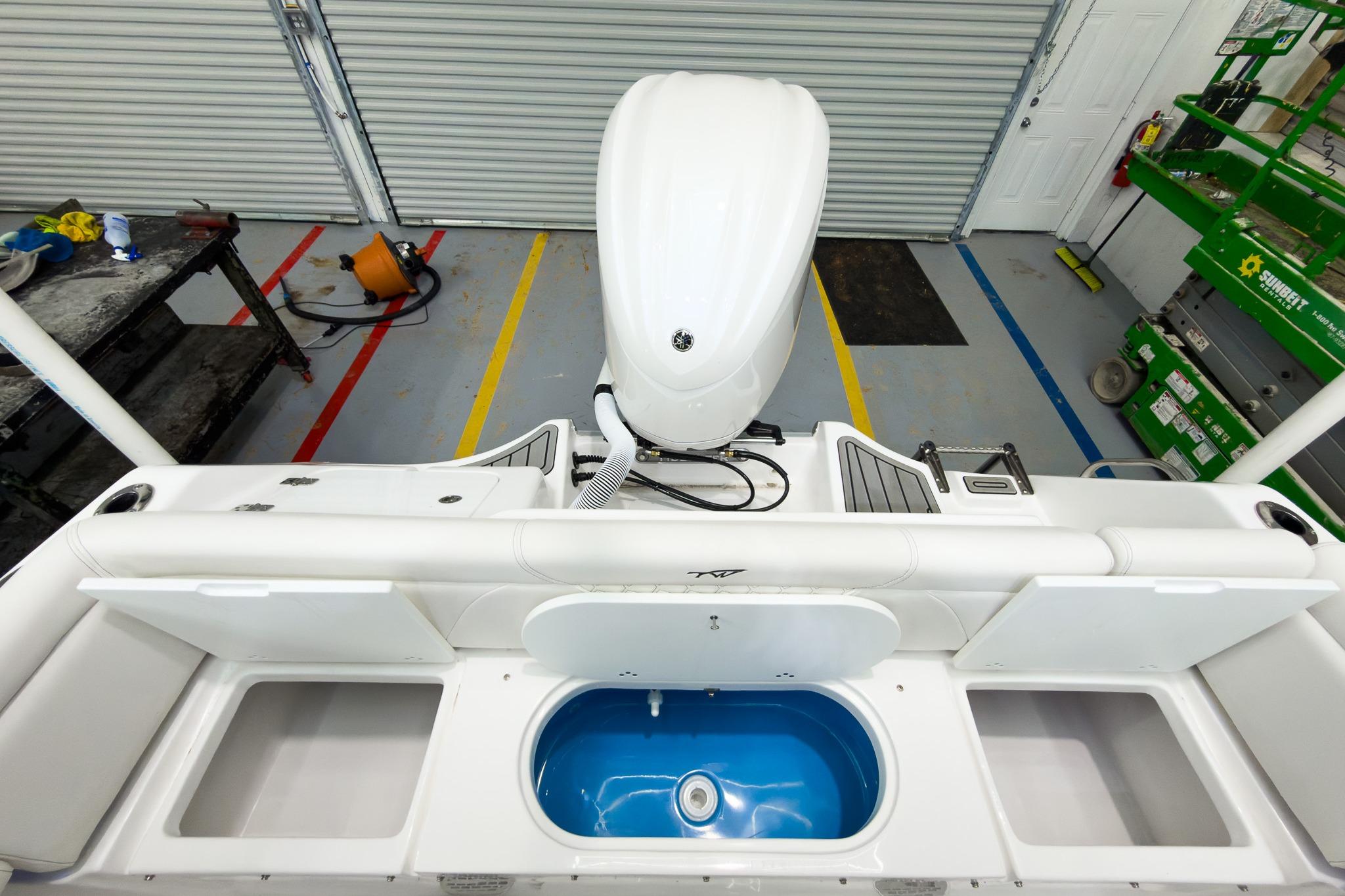 2026 Tidewater 232 LXF boat interior with storage compartments and motor in a garage.